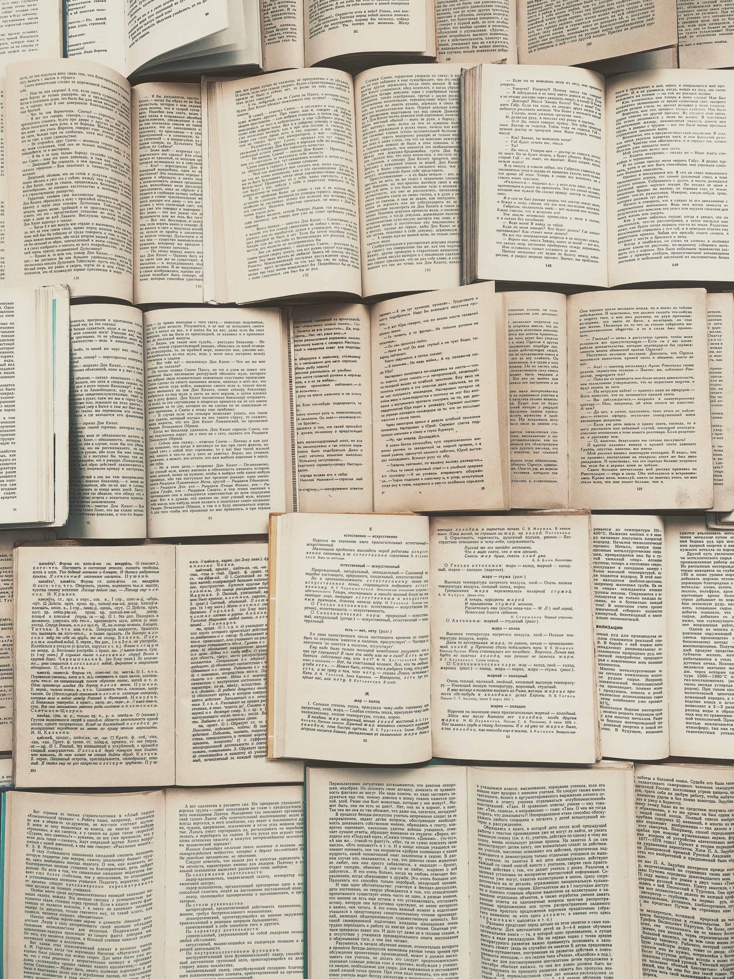 A collection of open books spread out on a surface, all written in Russian, with various pages visible containing dense text and some annotations.