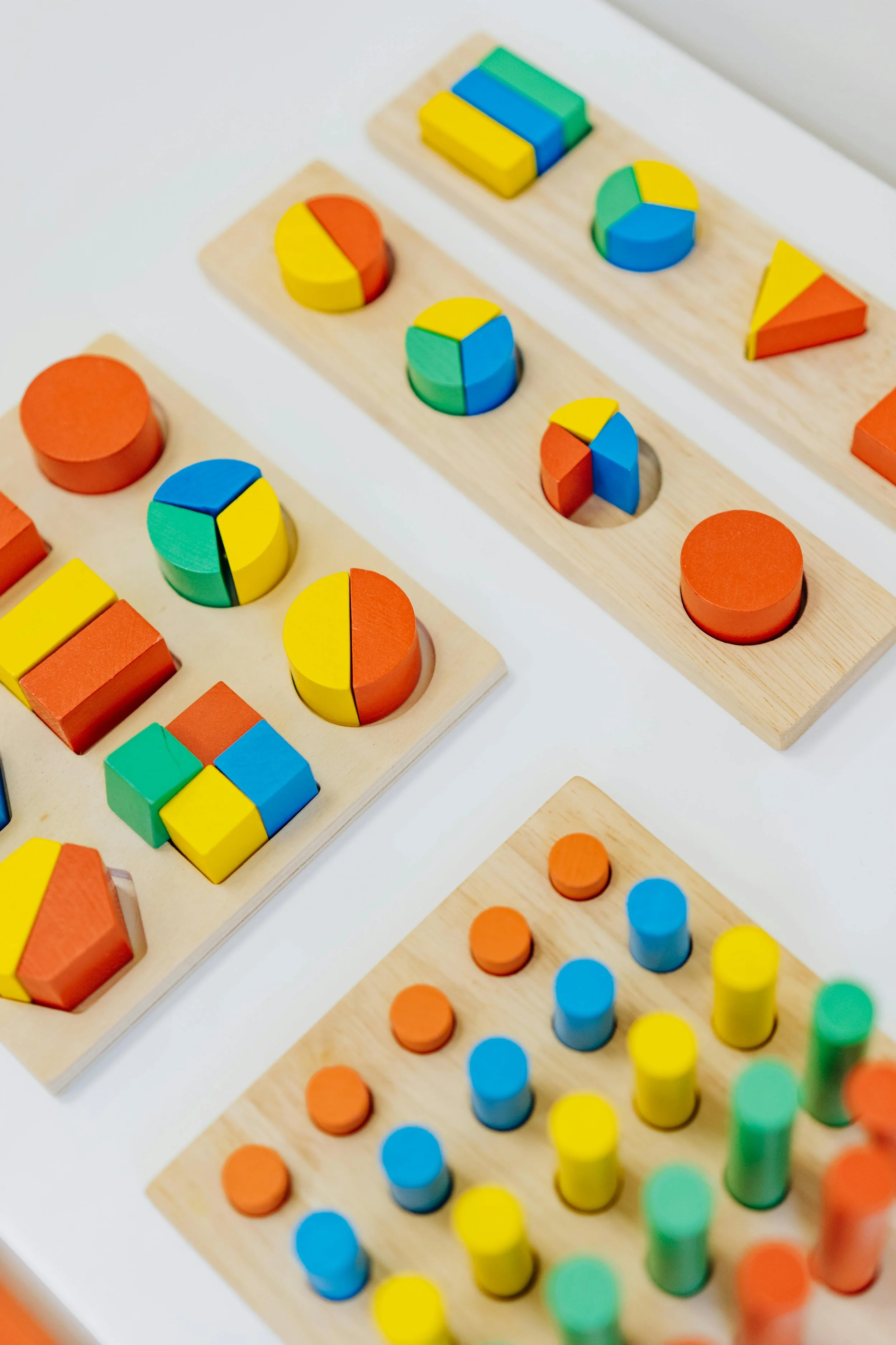 Colorful educational wooden toys with geometric shapes and patterns on white surface.