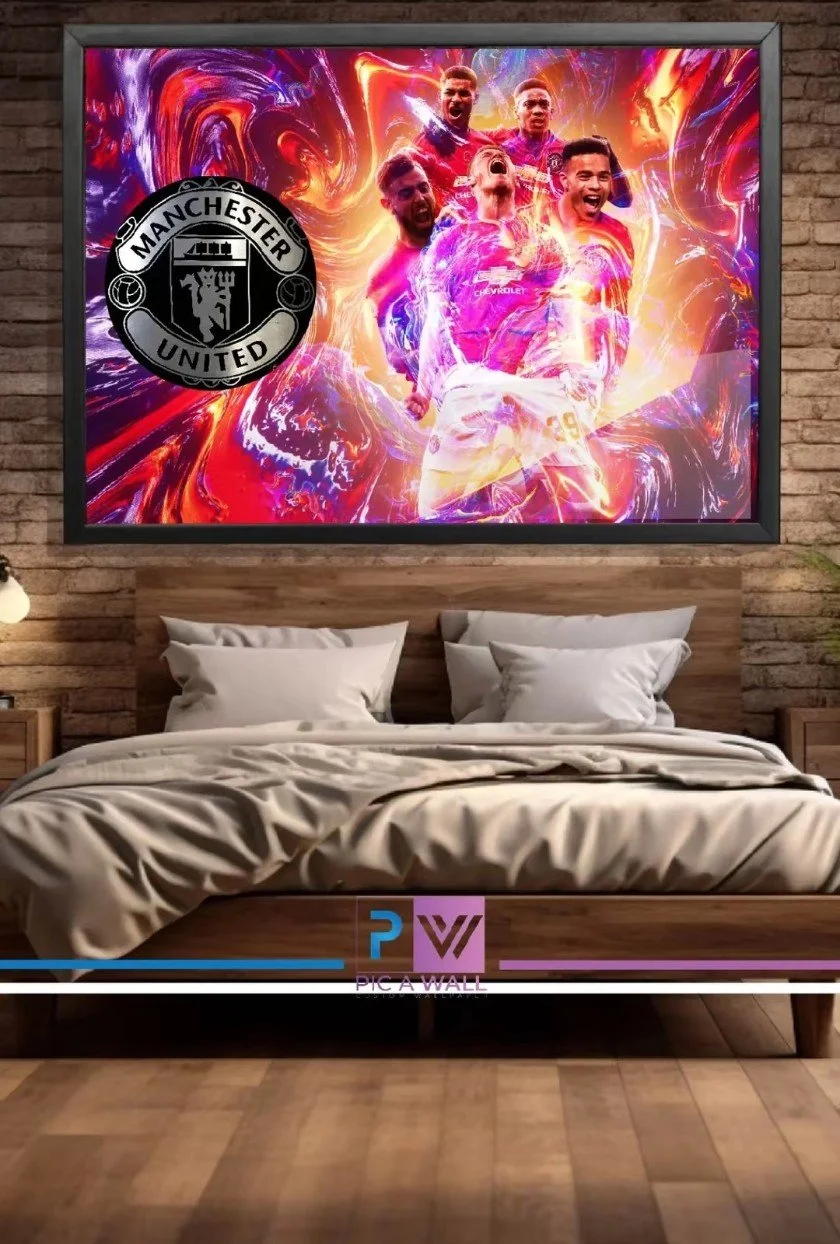 A digital mural featuring Manchester United soccer players in action with vibrant, swirling colors in the background. The Manchester United logo is prominently displayed on the left side of the artwork. The mural is mounted above a bed in a modern be