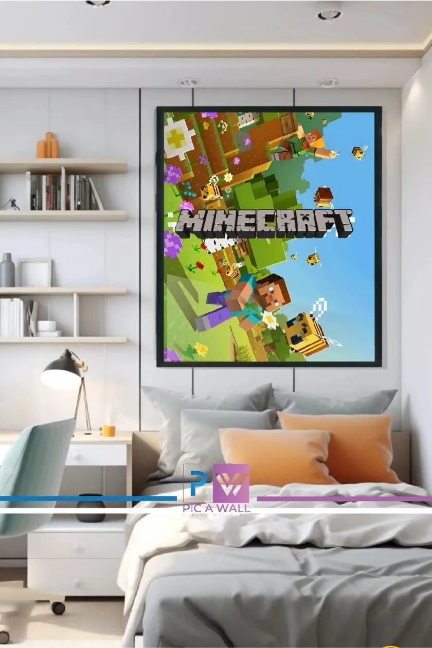 A bedroom with a wall-mounted Minecraft-themed artwork featuring blocky characters, trees, and animals. The room has a bed with beige and peach pillows, a white nightstand with a yellow cup, a desk with a lamp, and floating shelves with books and dec