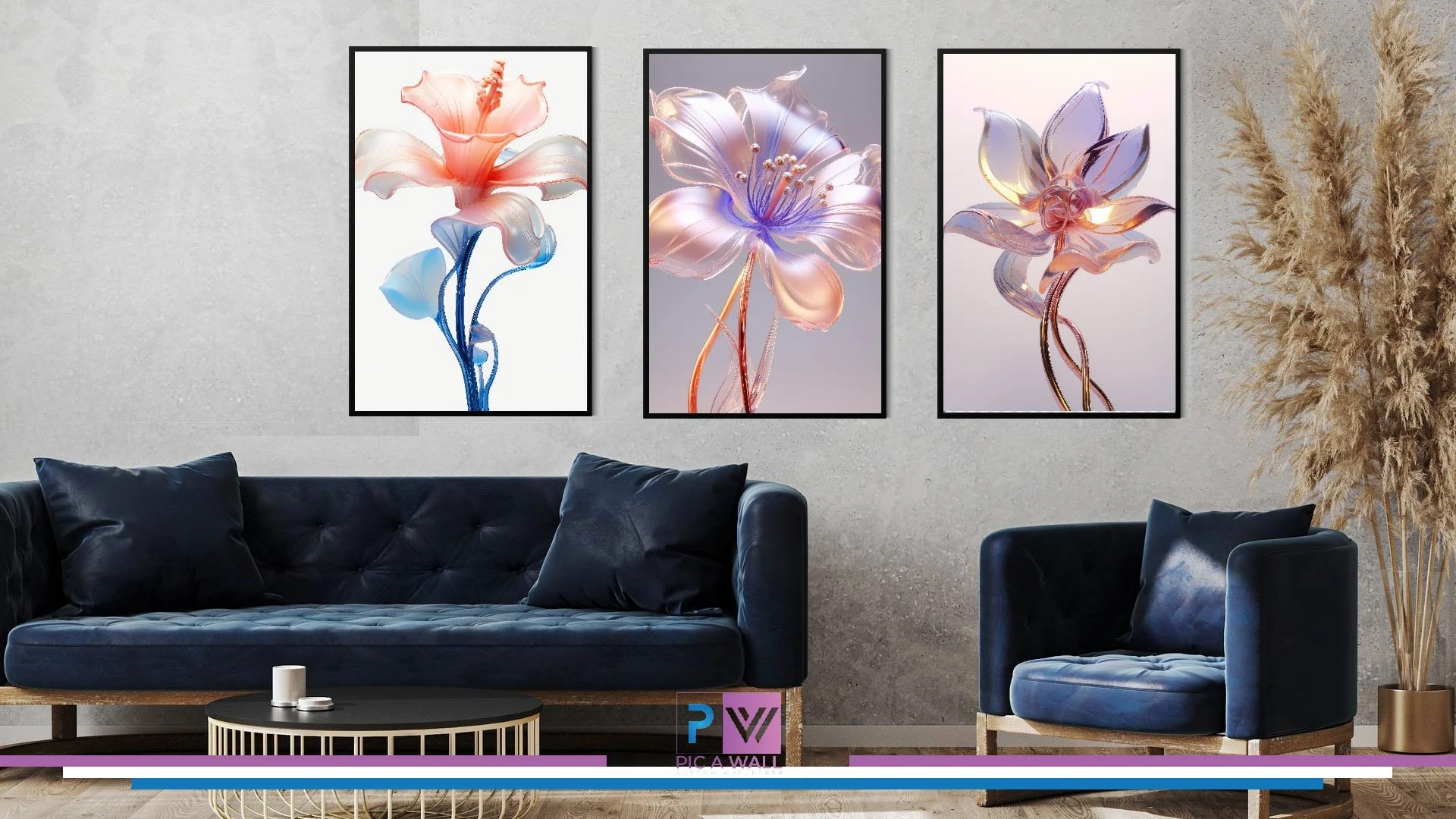 Living room with gray textured wall, three framed floral artwork featuring abstract pink and purple flowers, dark blue velvet sofa with matching pillows, and a dark blue armchair with a pillow. There is a round black coffee table with gold accents in front, and a tall beige pampas grass plant in a gold pot on the right side.