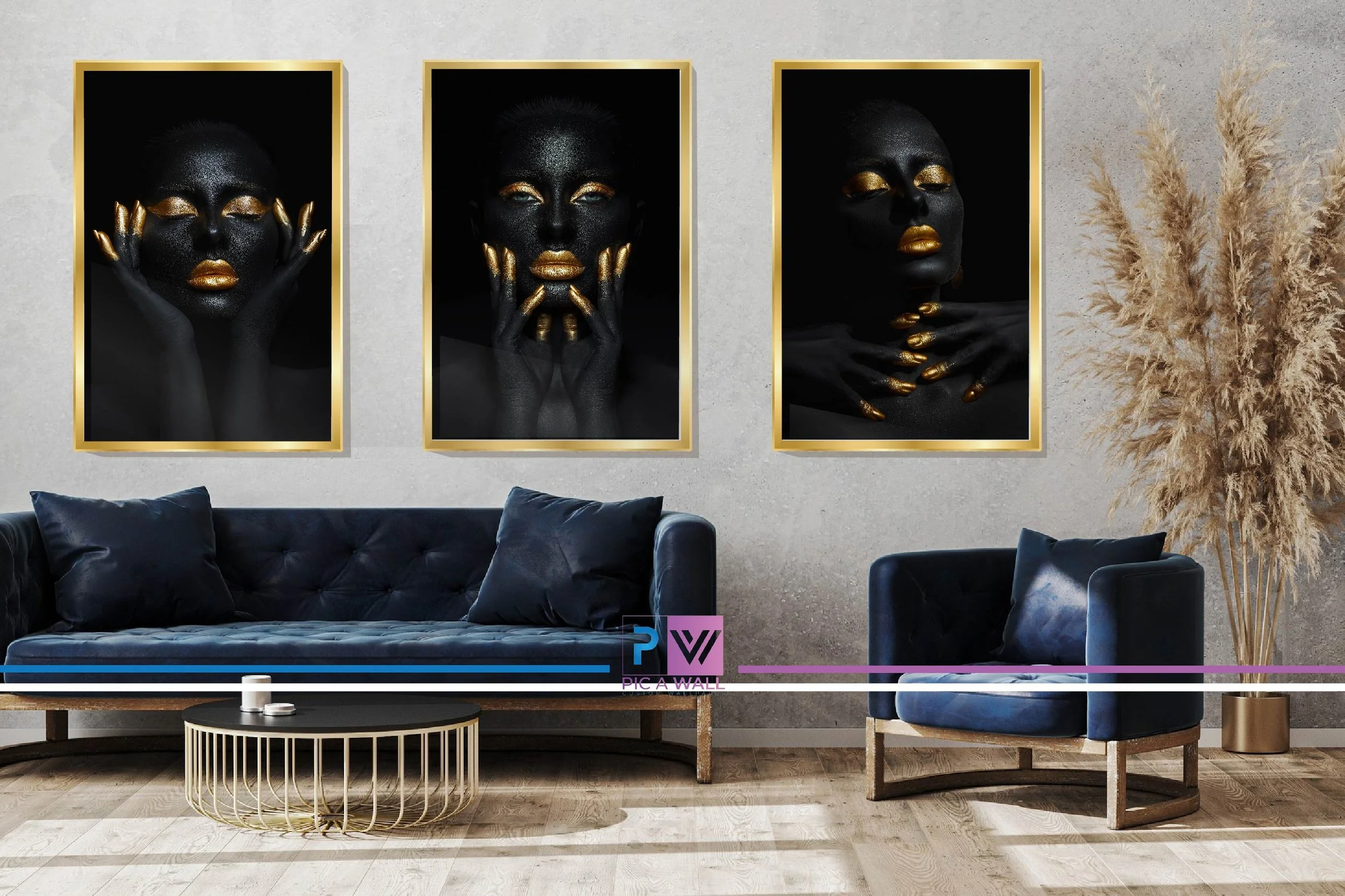 Modern living room with three large framed black and gold portraits of a woman with black skin and gold makeup, and a navy blue sofa with matching pillows, a round coffee table, and a tall beige pampas grass plant in a gold pot.