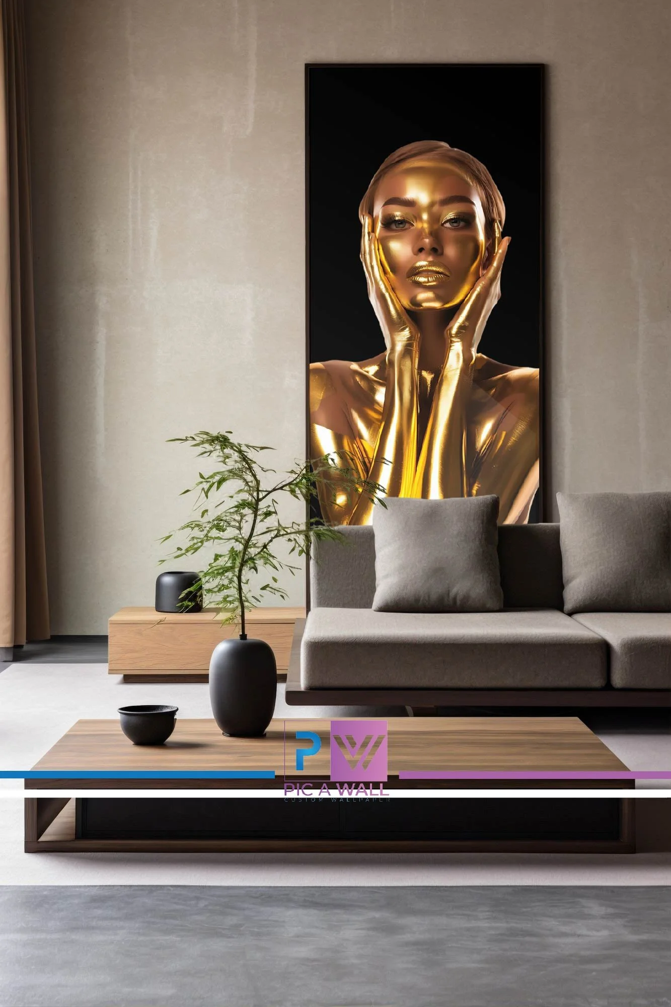 Modern living room with a large artwork of a woman with gold painted skin, framed in black, hanging on a beige wall. The room features a gray sofa, a wooden coffee table with decorative black vases and a potted plant, and a beige carpet.