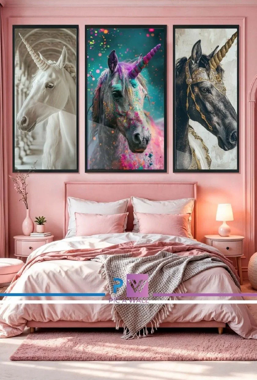 A pink bedroom with a bed, pillows, and a blanket, decorated with three framed horse portraits on the wall above the bed, including a white unicorn, a colorful unicorn, and a black unicorn with gold accents.