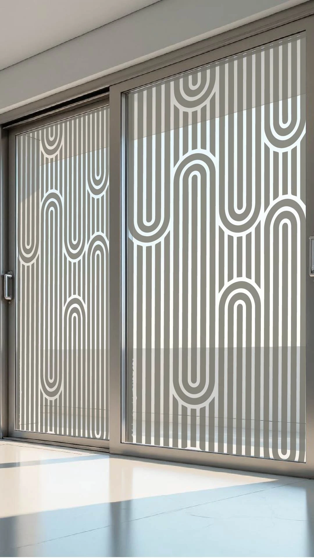 Sliding glass doors with a geometric pattern of white lines forming arches and vertical stripes, allowing sunlight to cast shadows on the floor.
