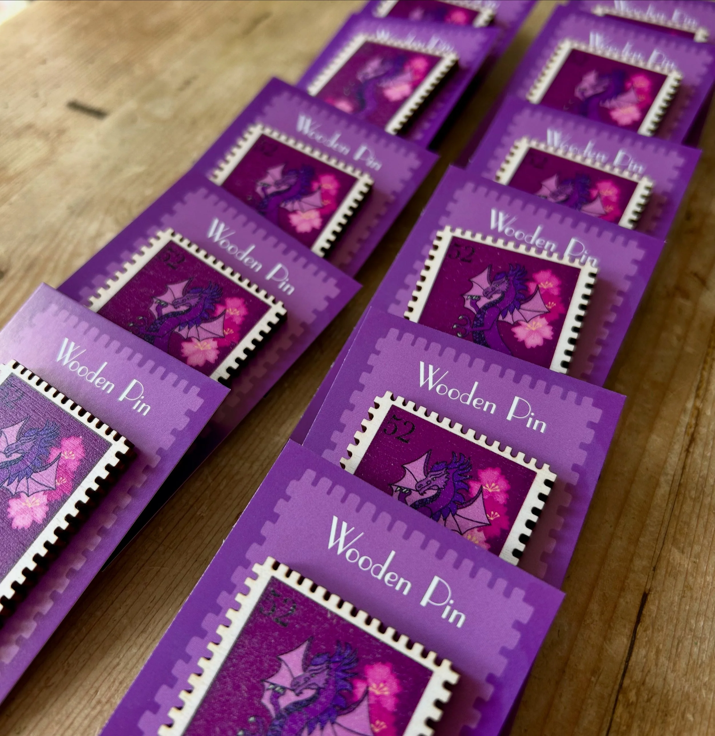 Purple packaging labels with a dragon illustration and pink cherry blossoms, indicating the boxes contain wooden pins.