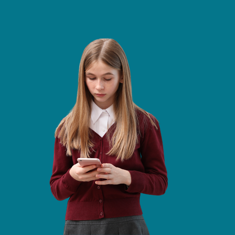 Young girl with long blonde hair wearing a white shirt and maroon cardigan, looking at her smartphone against a blue background.