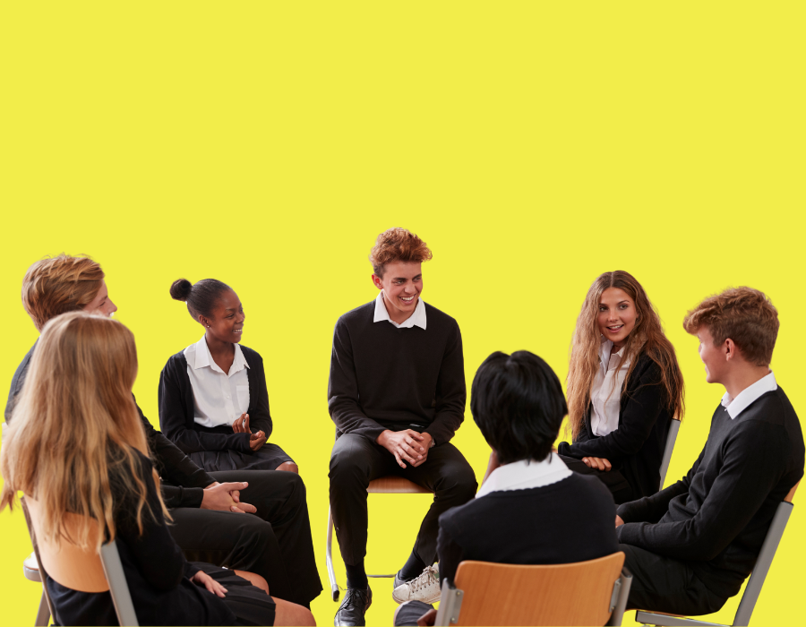 Group of diverse students in school uniforms sitting in a circle, engaged in a discussion or group activity, against a bright yellow background.