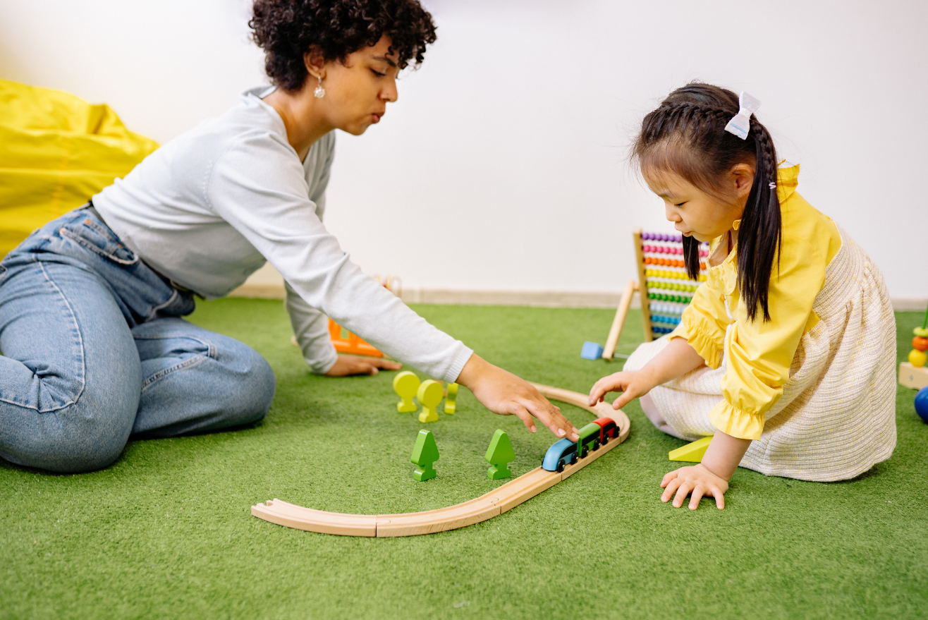 an adult and child playing with trains together on the indoor turf.