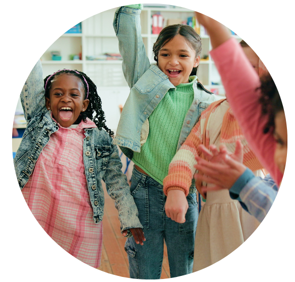 Children jumping up and down raising their hands and dancing. Everyone is smiling and looks joyful. 