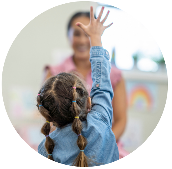 A child excitedly raising her hand in class.