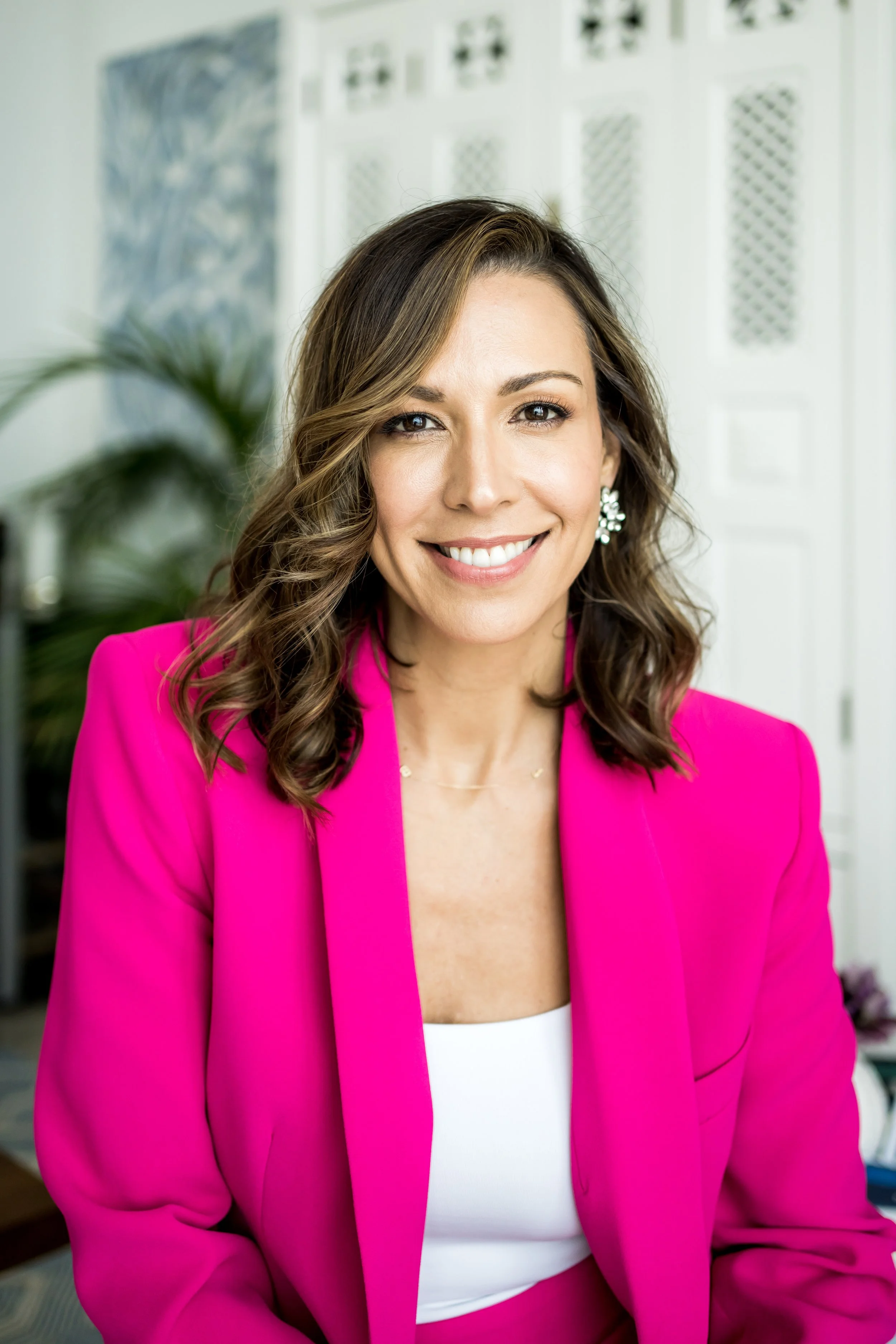 A professional picture of Dr Melissa Giglio. She is smiling at the camera and wearing a bright pink suit.