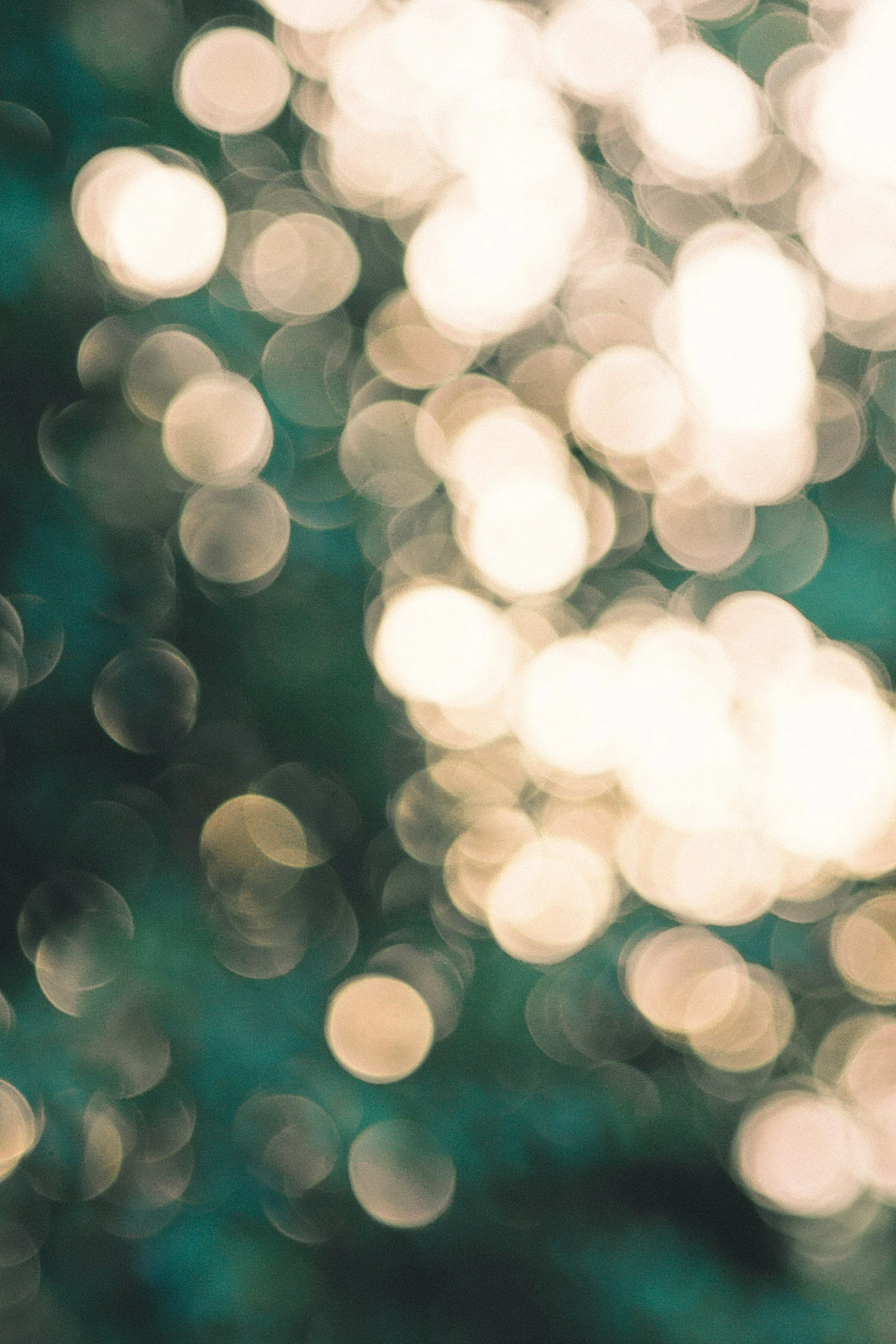 Blurred background of warm white and teal light bokeh circles.