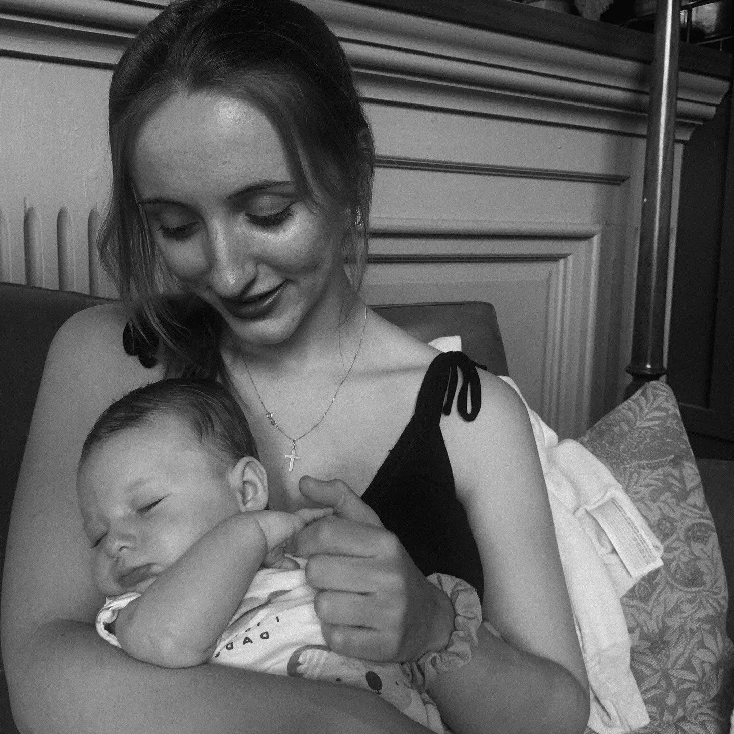 A woman holding a sleeping newborn baby in her arms.