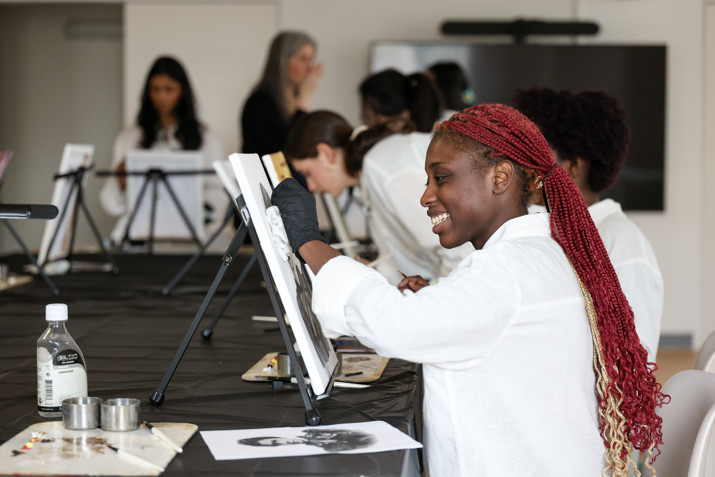 A group of women painting on canvases at an art class.