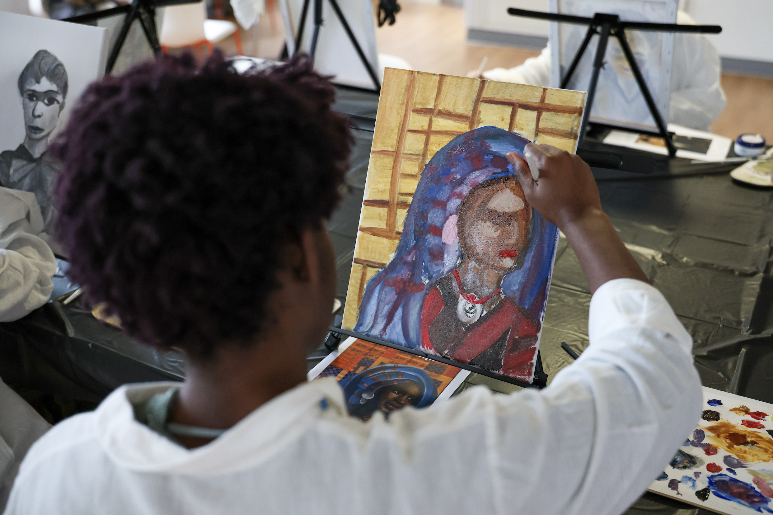 Team member painting in a guided painting workshop, with a portrait of a woman on a canvas.