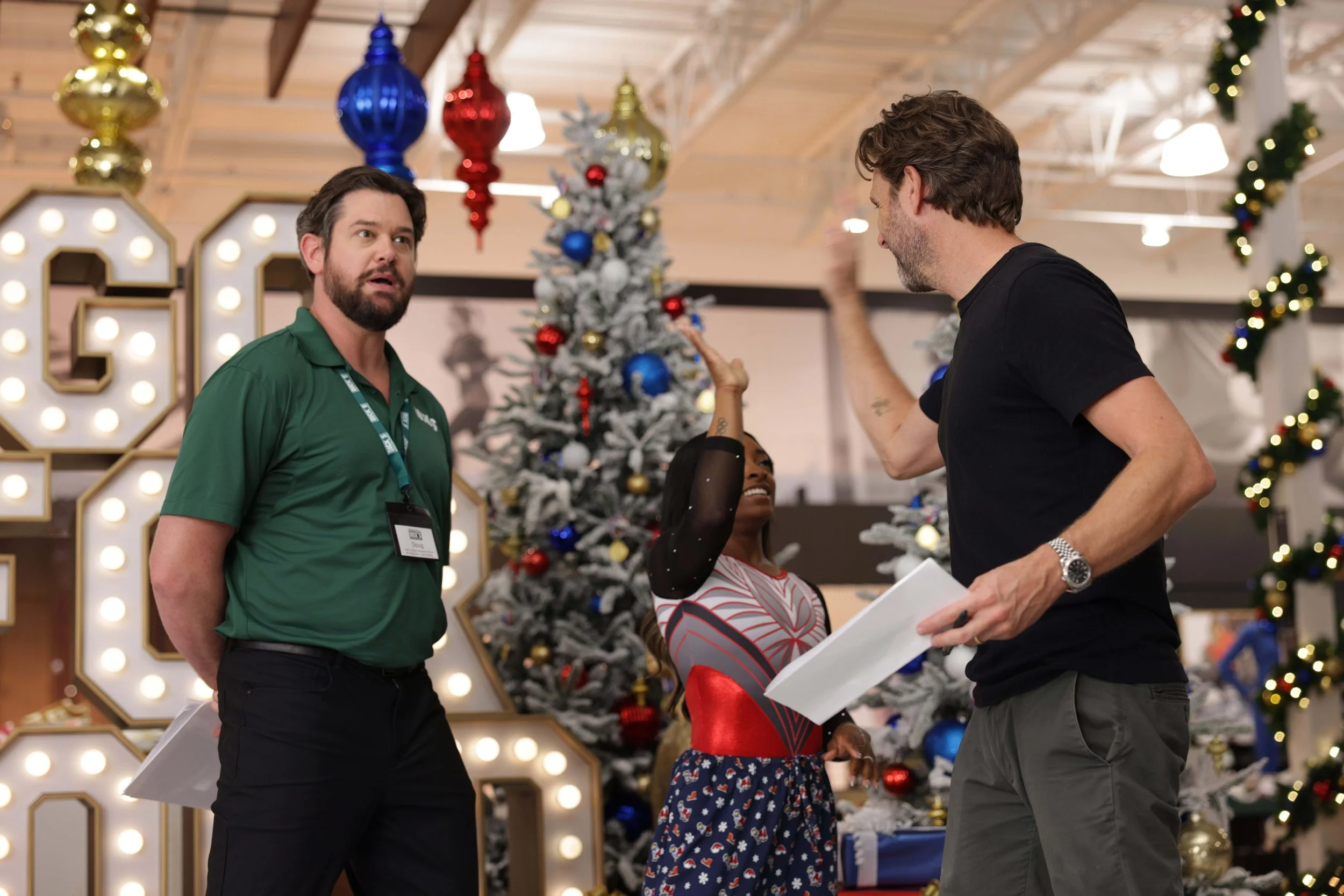 Two men arguing or having a disagreement in a retail store decorated for Christmas, with a woman trying to mediate. There are Christmas trees and holiday decorations in the background.