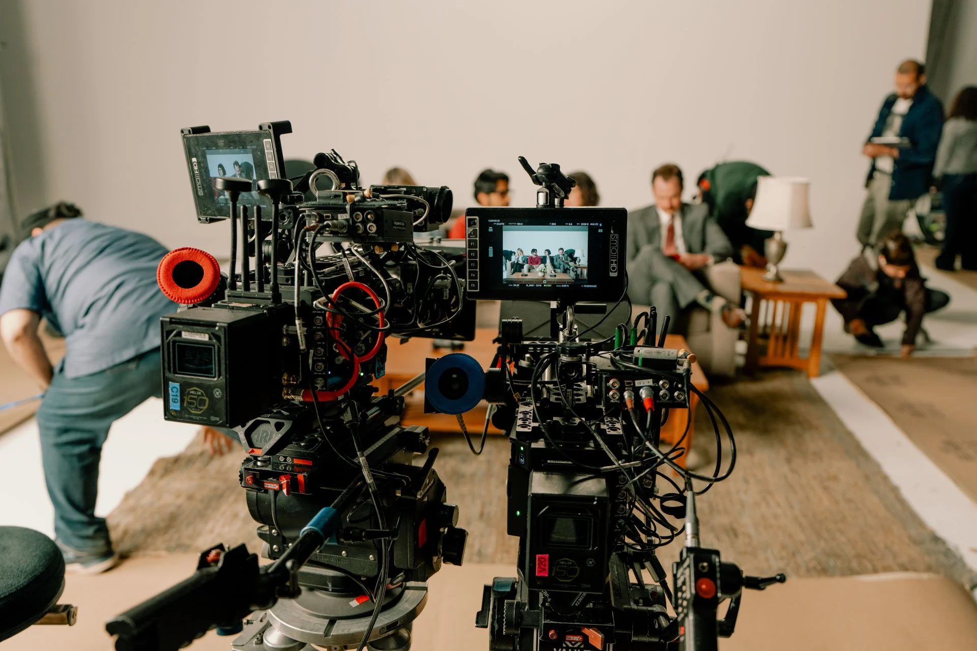 A camera setup on a film or video shoot with crew and actors in the background.