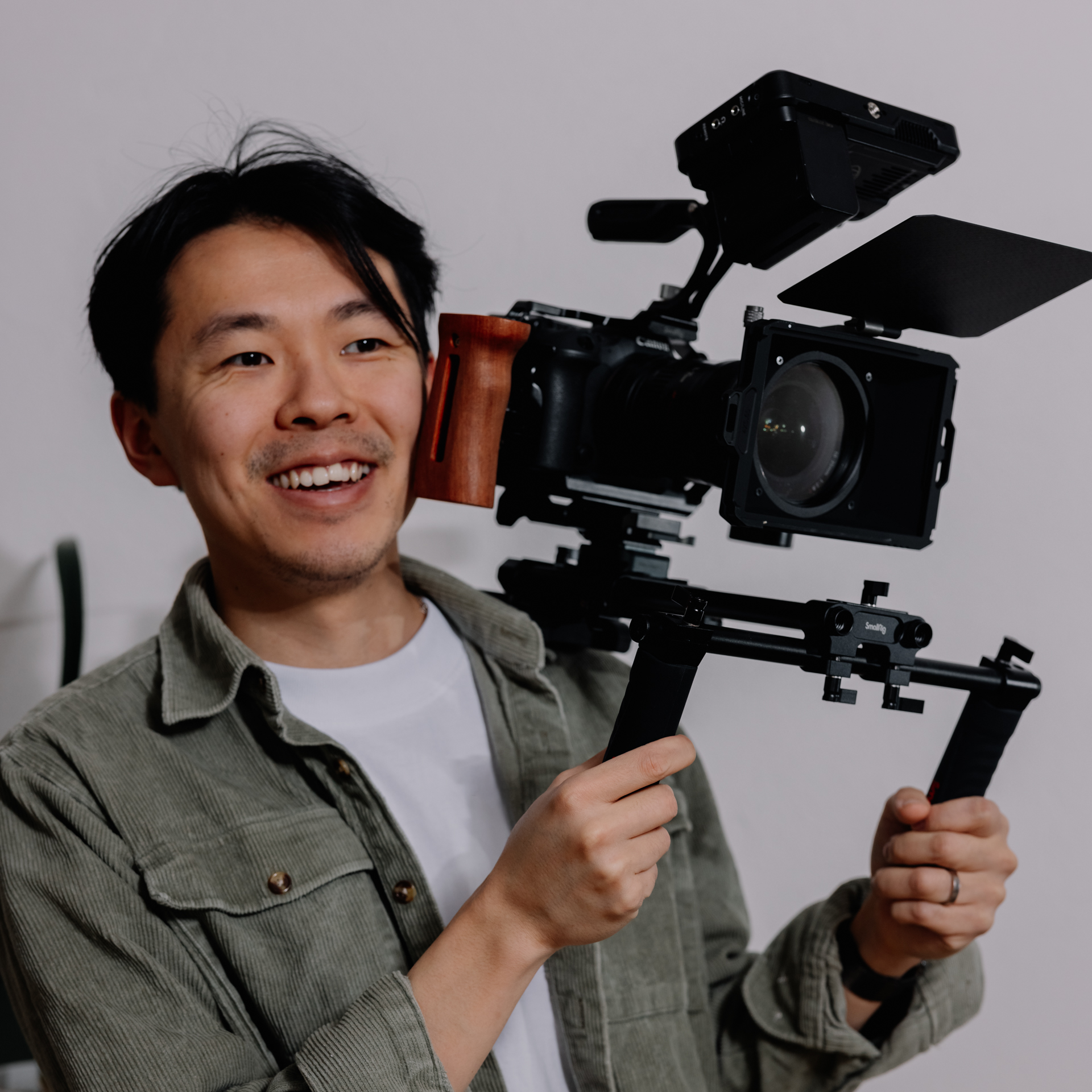 A man smiling and holding a professional video camera on a stabilizer.