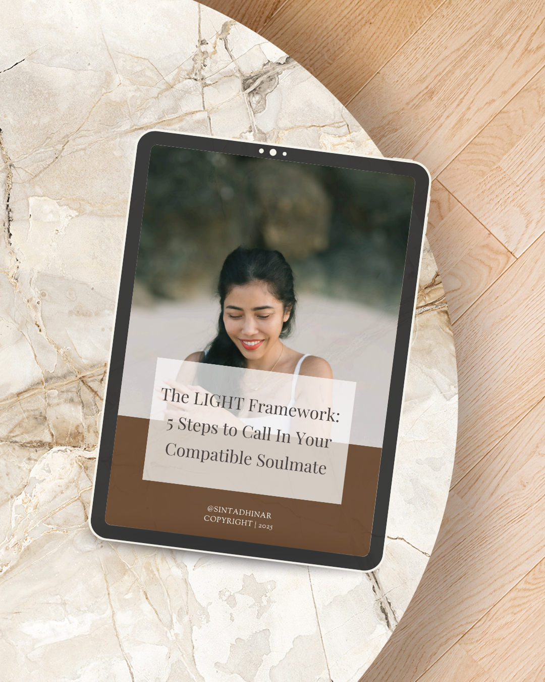 Tablet displaying a woman smiling outdoors with a guide titled 'The LIGHT Framework: 5 Steps to Call In Your Compatible Soulmate,' copyright 2023.