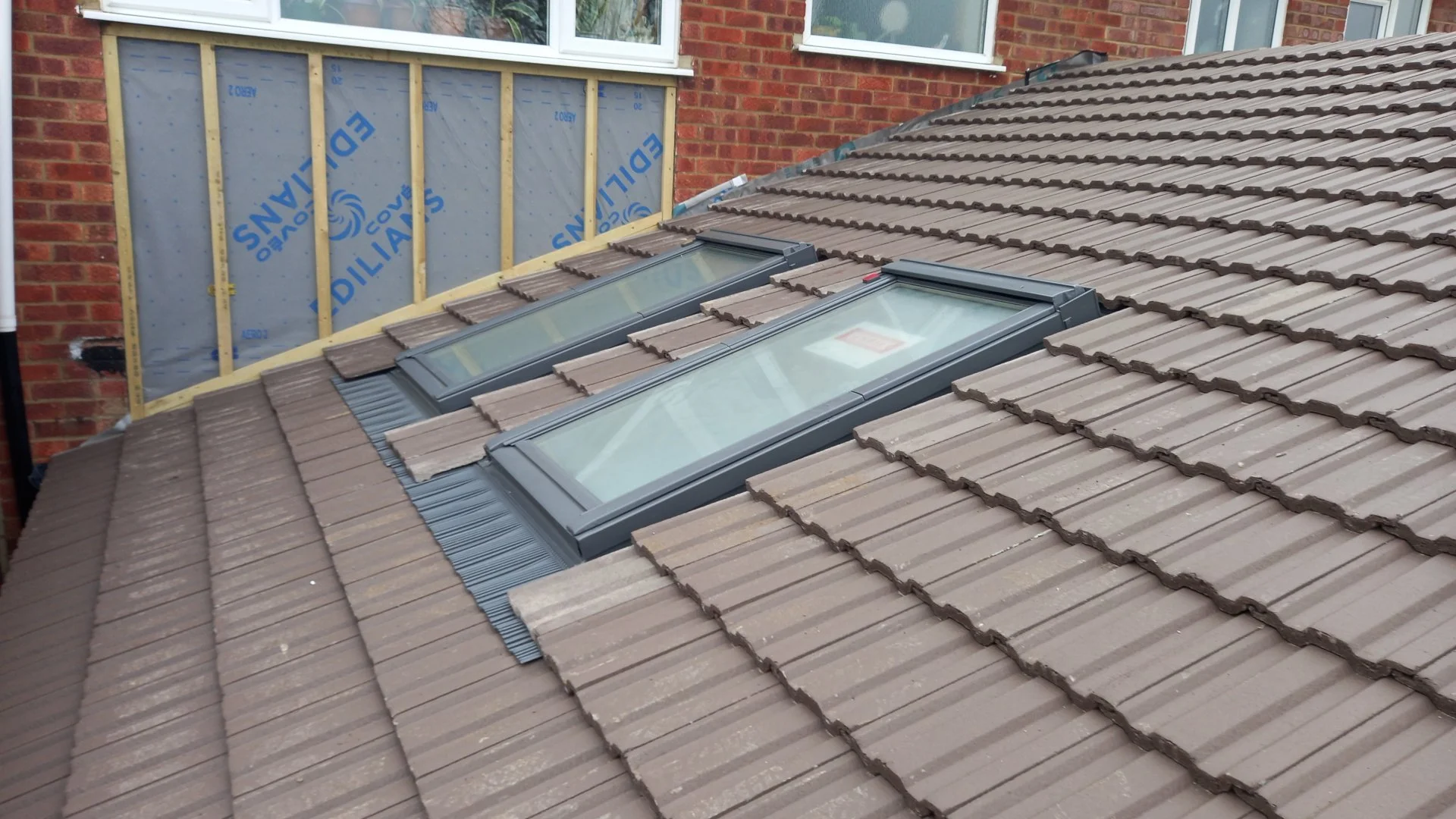 Roof with two skylights and a section of wall with unfinished window opening.
