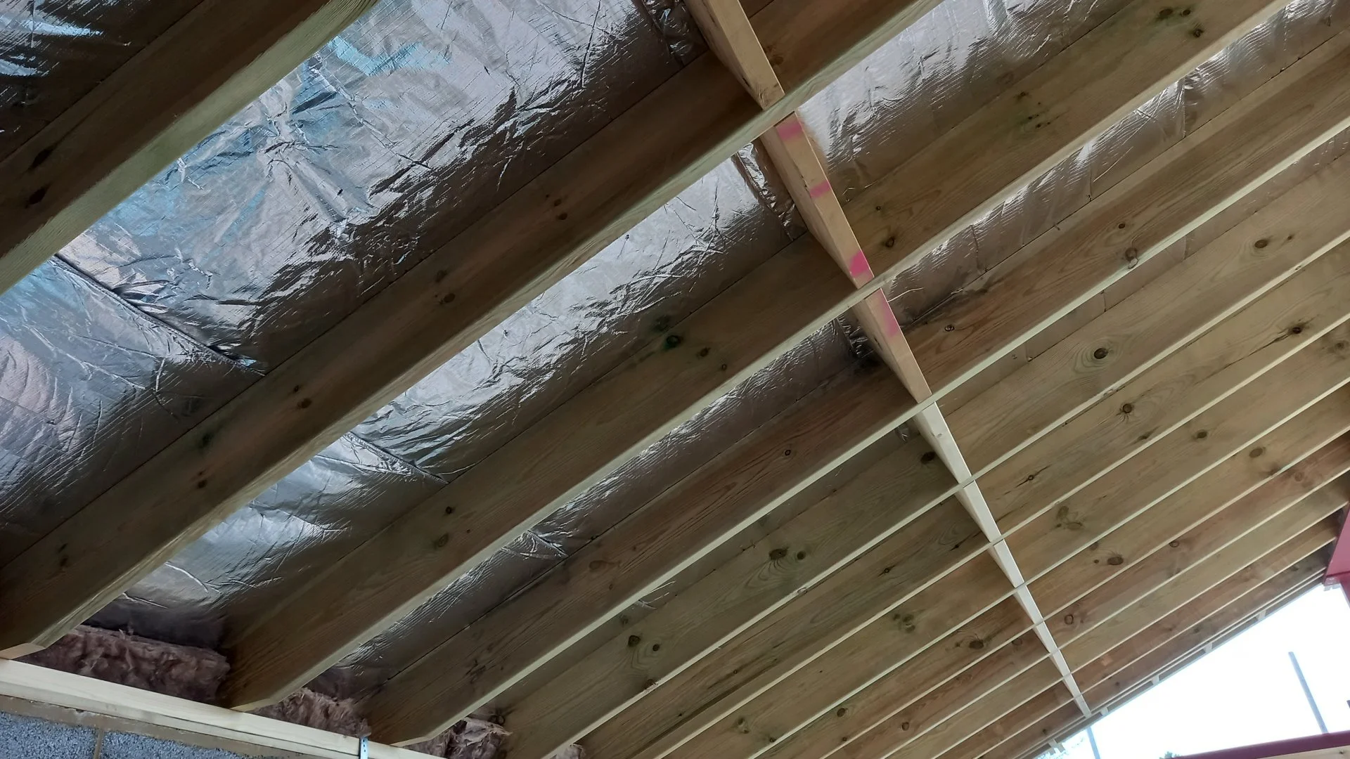 Wooden ceiling framework with insulation and vapor barrier.