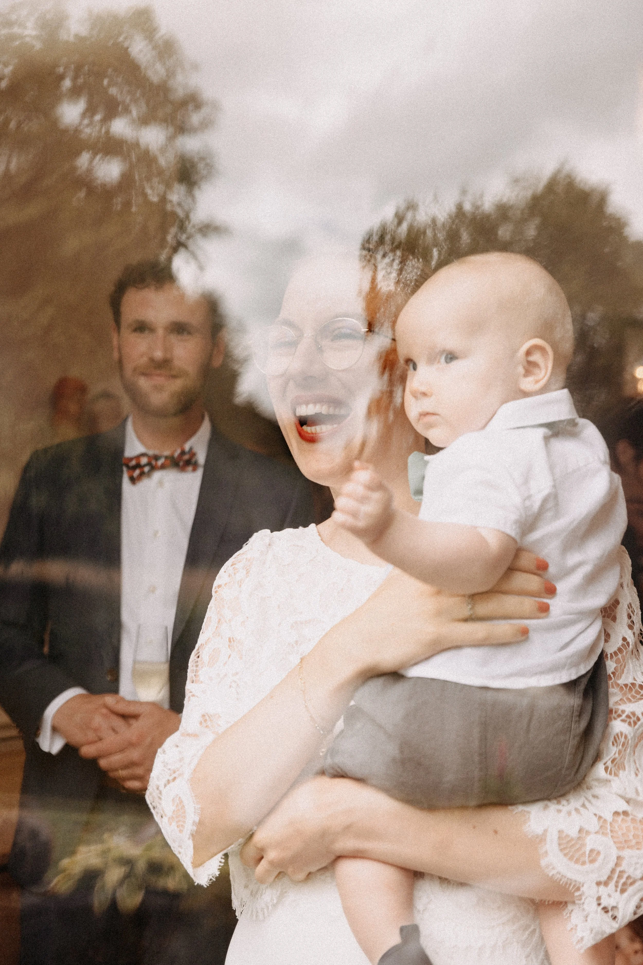 Une famille, comprenant un homme, une femme et un bébé, vue à travers une fenêtre lors d'un événement social ou une célébration.