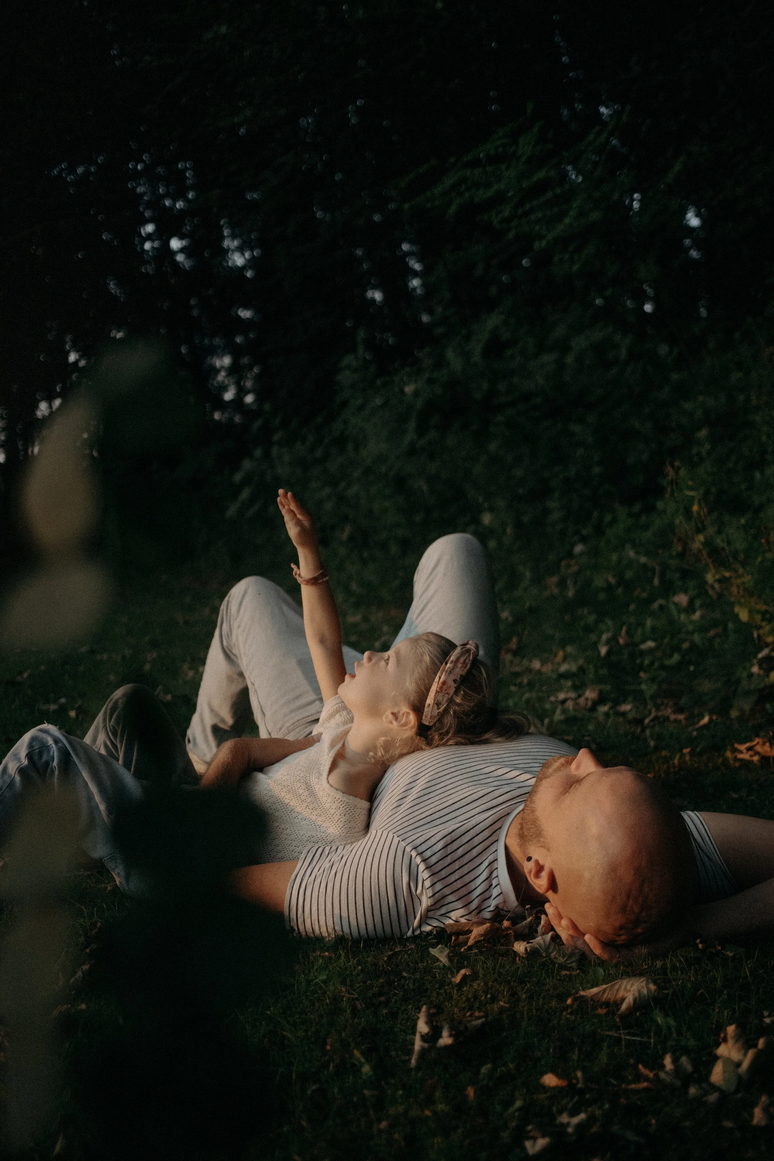 Un homme et une jeune fille allongés sur l'herbe dans un parc, la nuit, partagent un moment de calme et de complicité.