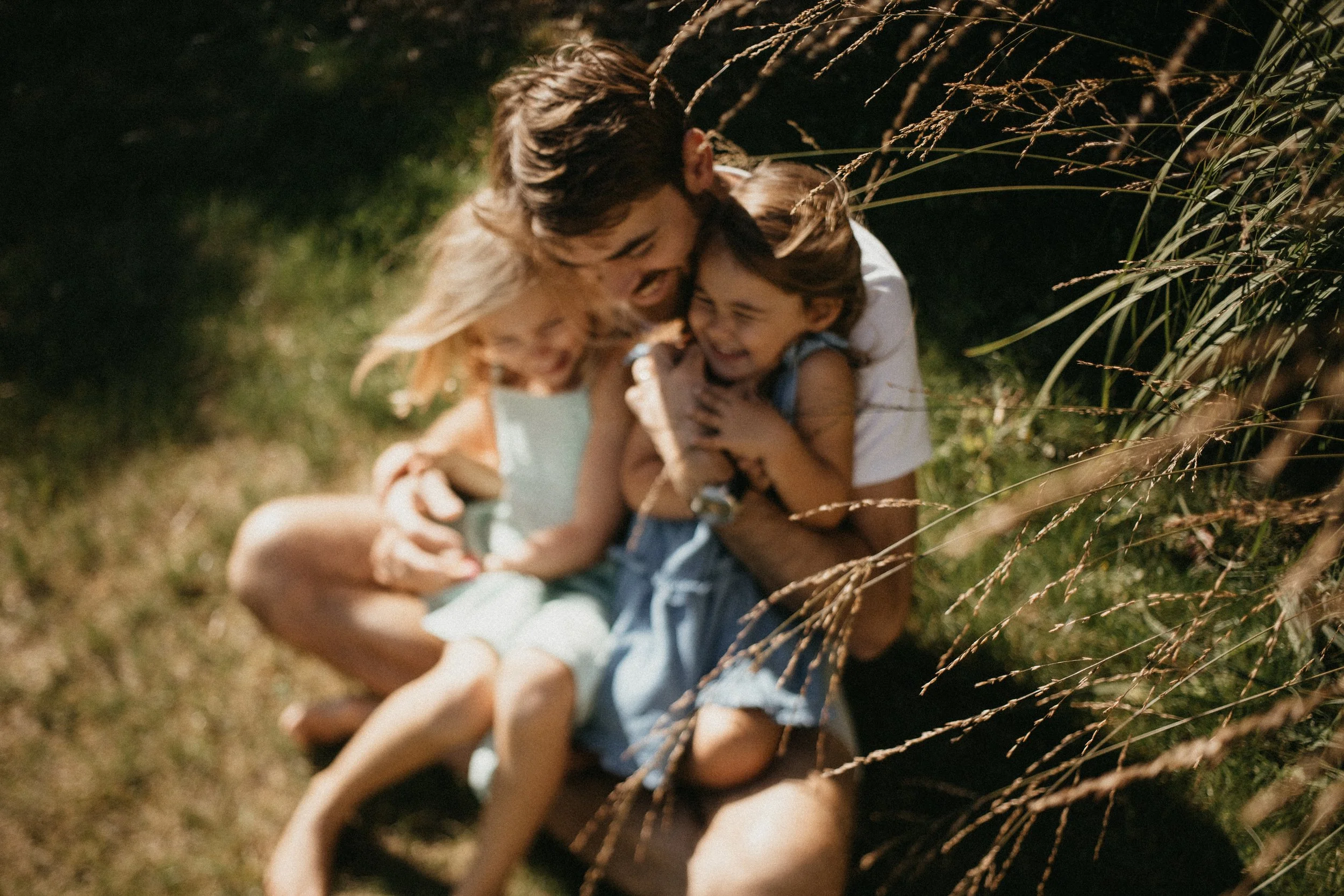 Un adulte et deux enfants, rire et jouer de façon joyeuse dans un champ d'herbe.