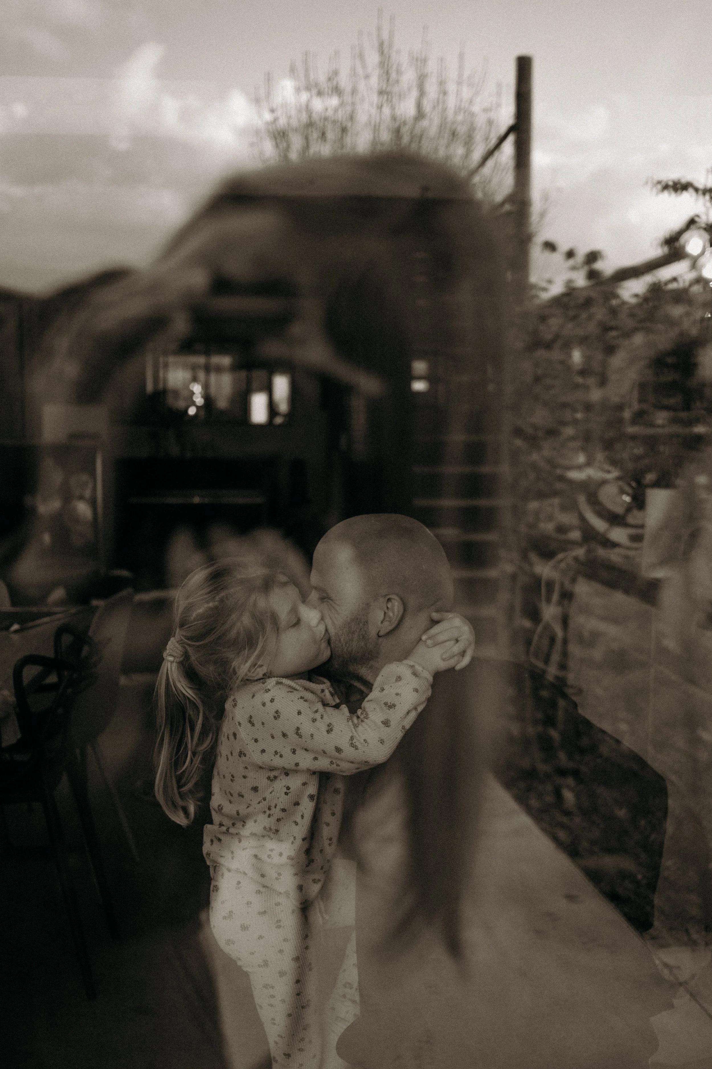 Un enfant et un adulte s'embrassent tendrement à travers une vitre.