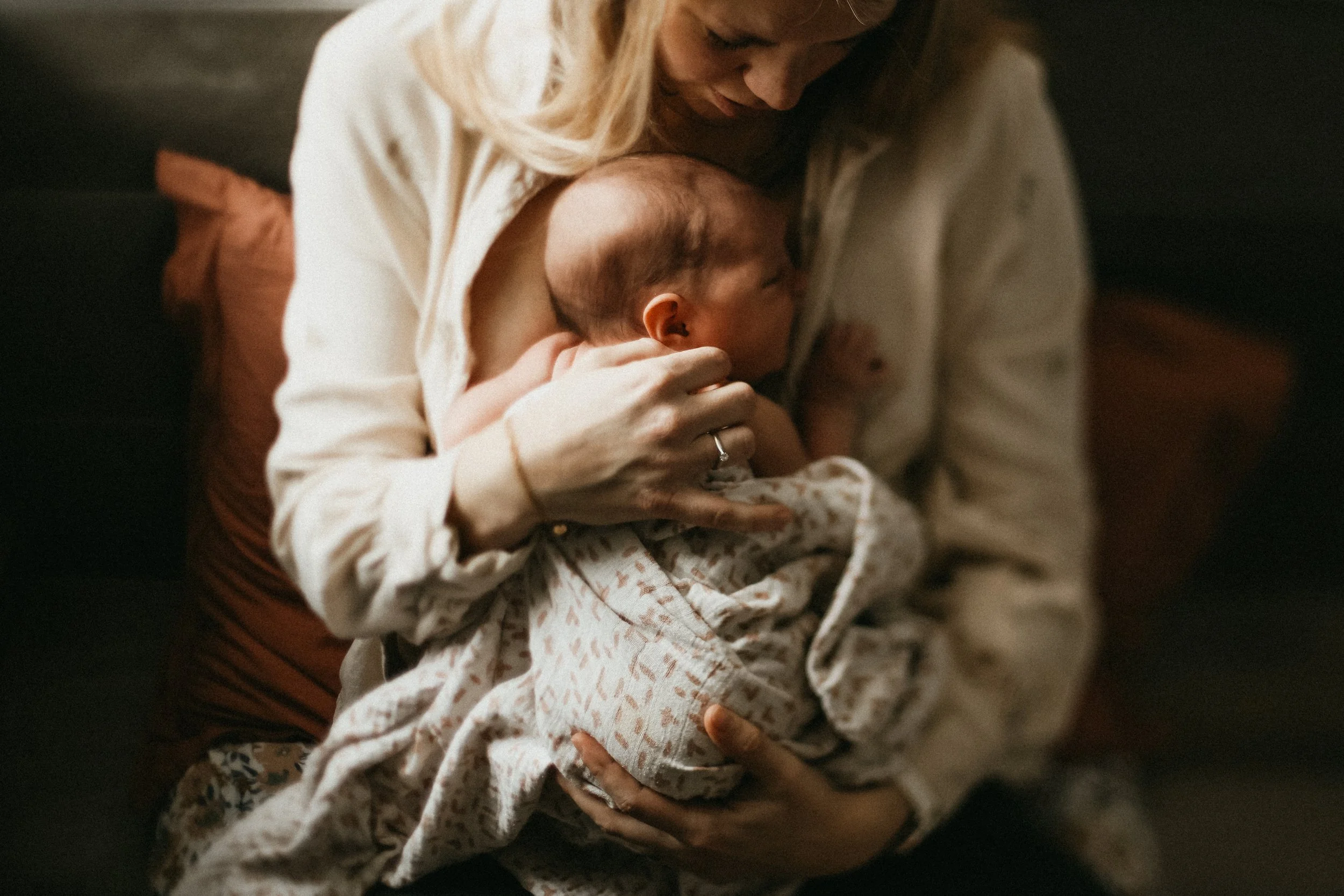 Une femme enceinte tient un bébé dans ses bras, lui donnant un câlin affectueux dans une ambiance chaleureuse et intime.