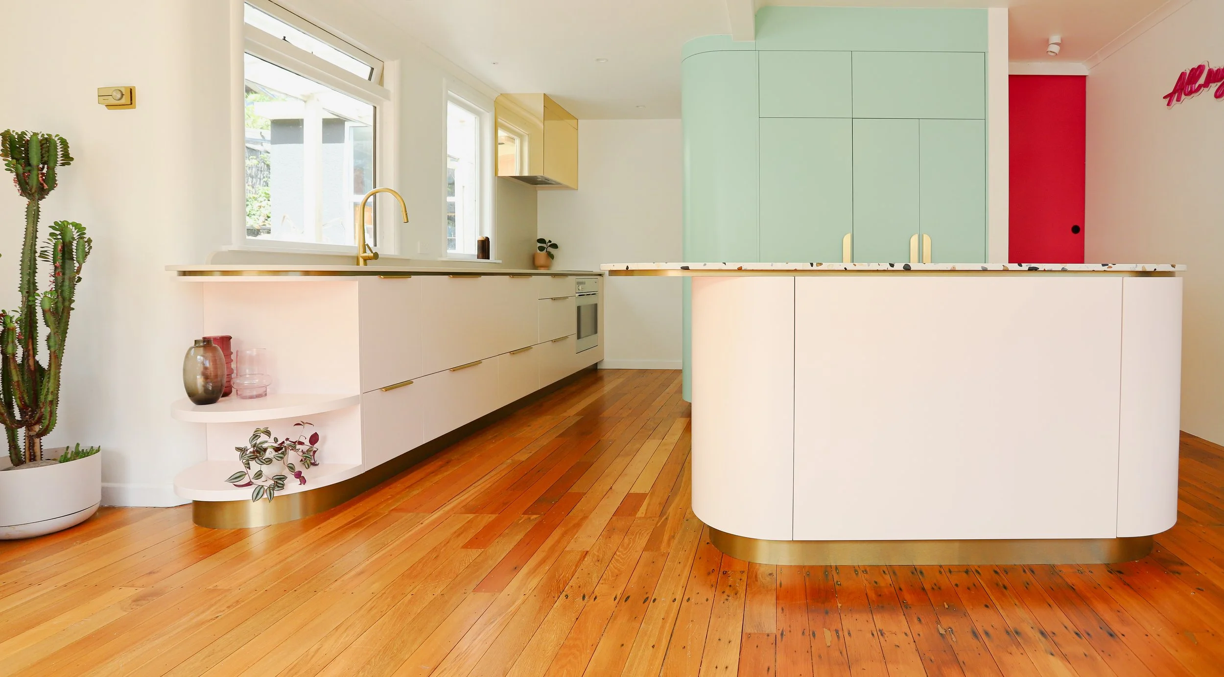 Pink and mint kitchen with wooden floors, brass hardware and details