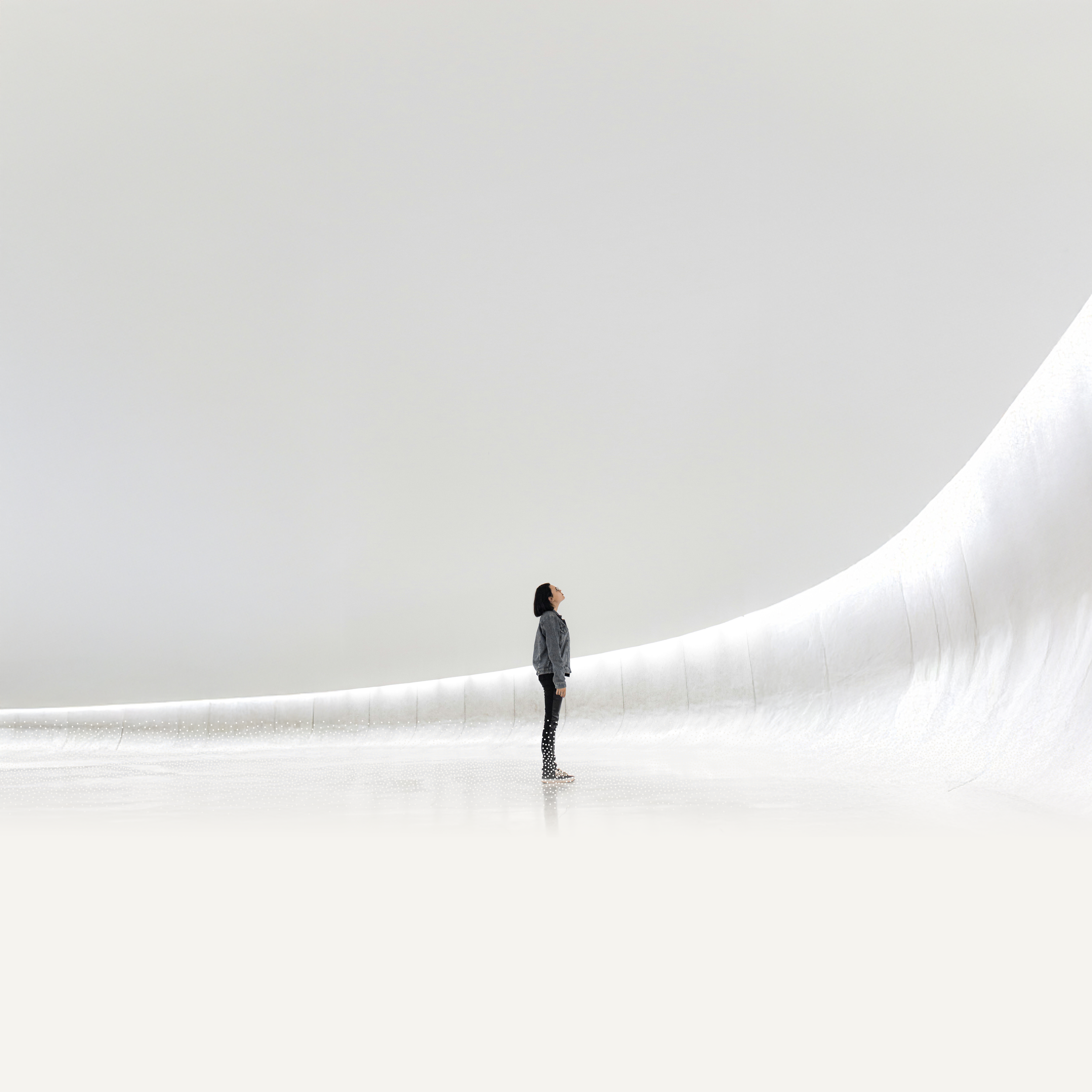 white space one person stands in the center looking up, weisser leerer raum mit person in der mitte die hinauf blickt