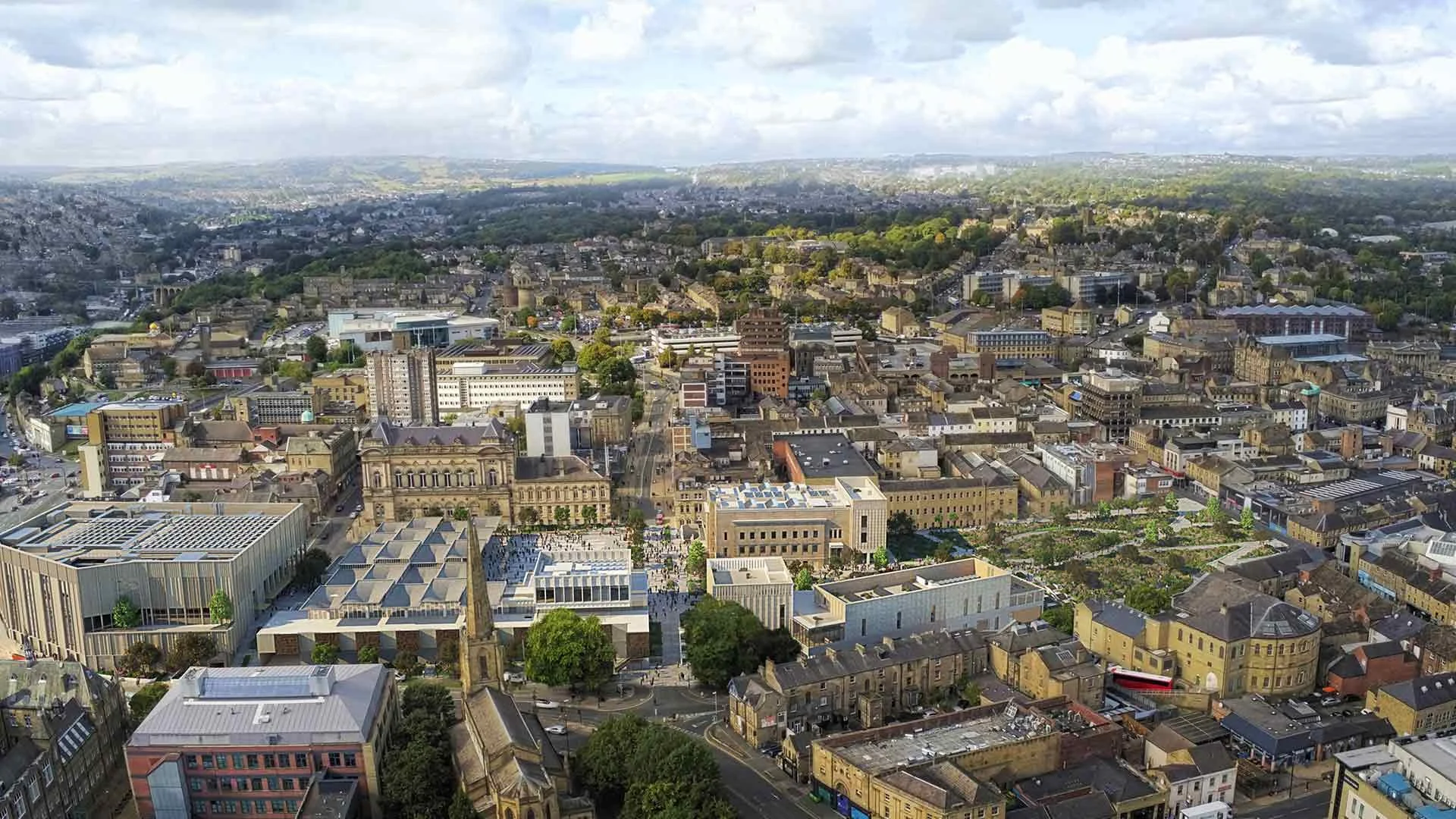 Aerial view of a cityscape with a mix of historic and modern buildings, streets, trees, and hills in the background under a partly cloudy sky.