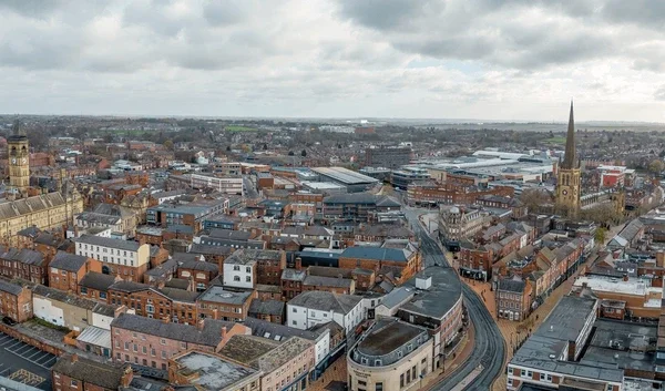 Aerial view of a city with old and modern buildings, a church steeple, and cloudy sky.