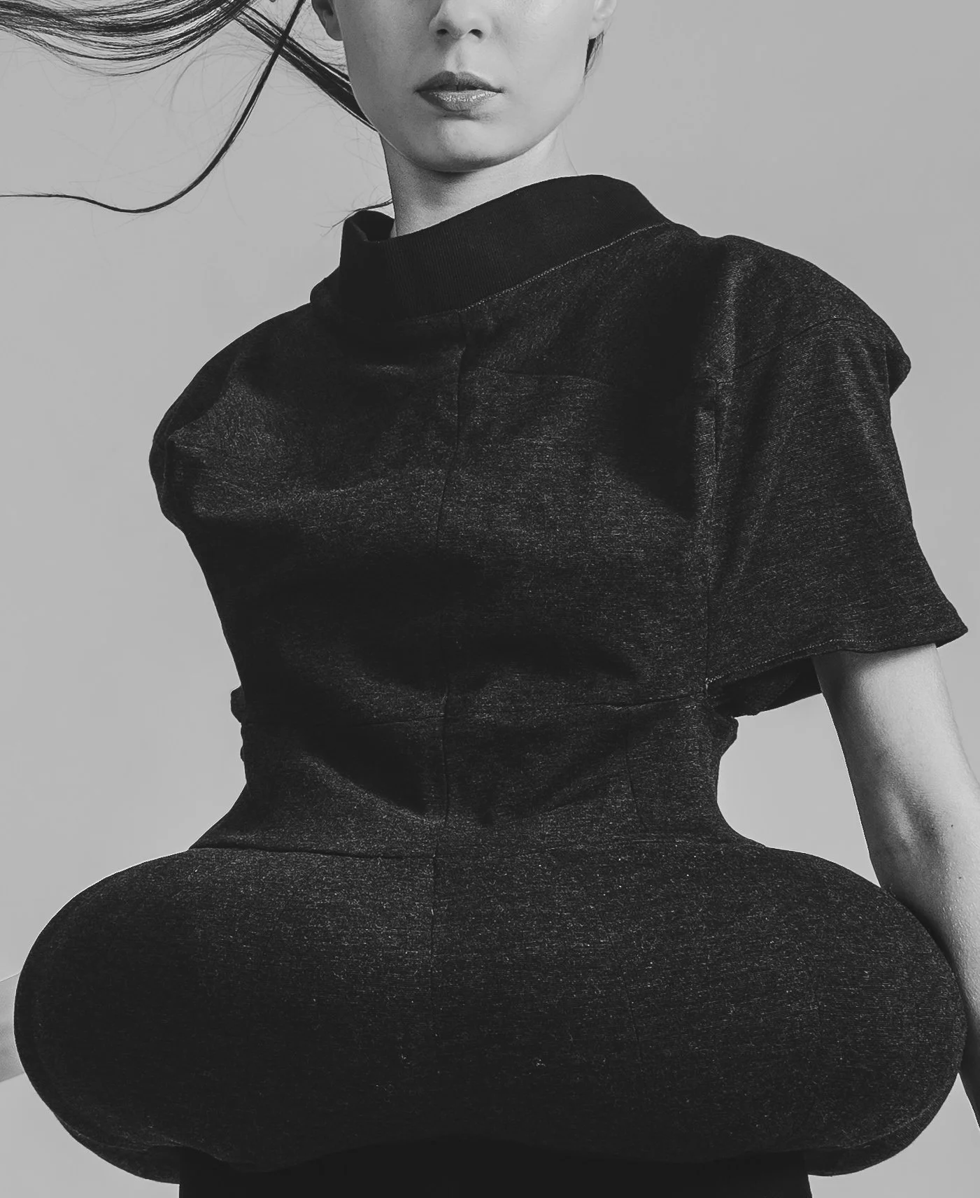 Une femme en noir et blanc, vue de la taille en haut, portant un sweat-shirt noir