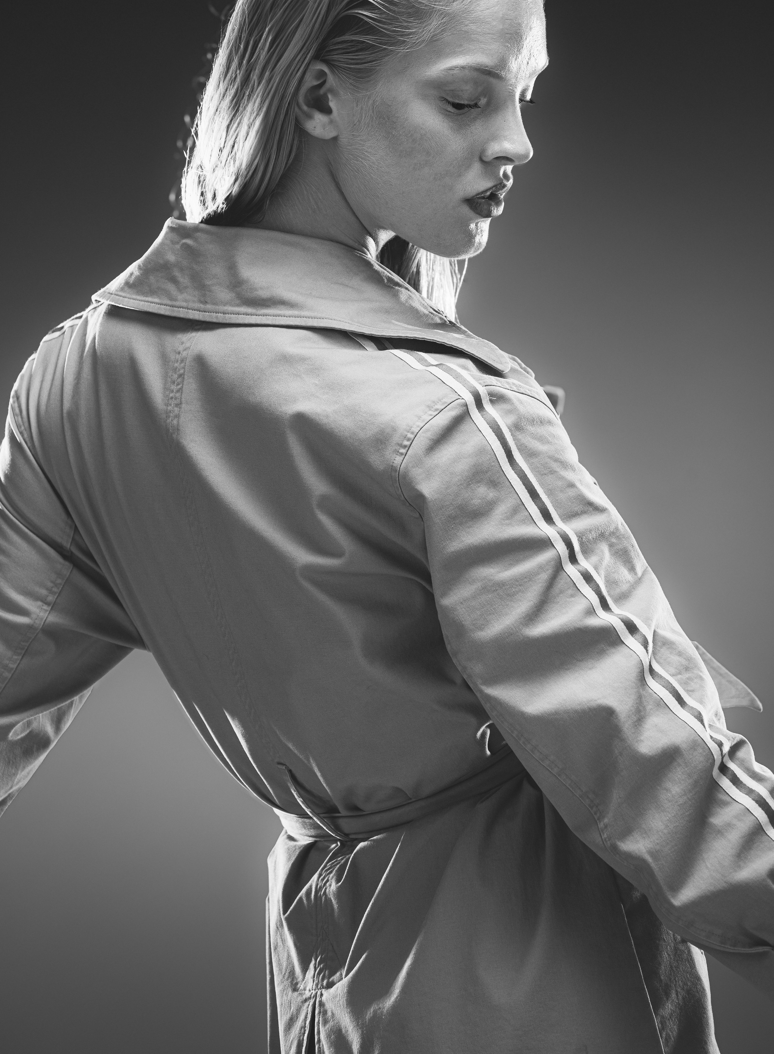 Femme en trench-coat, vue de dos, en noir et blanc.