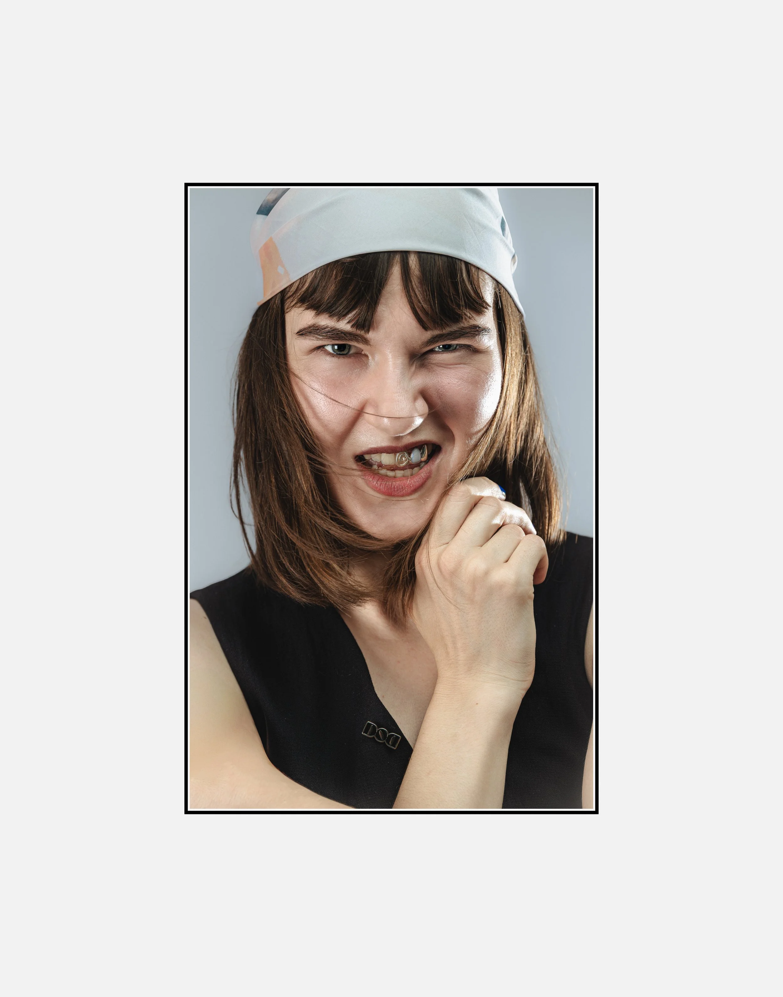 Jeune femme avec un foulard blanc, expression faciale expressive, portant une veste noire.