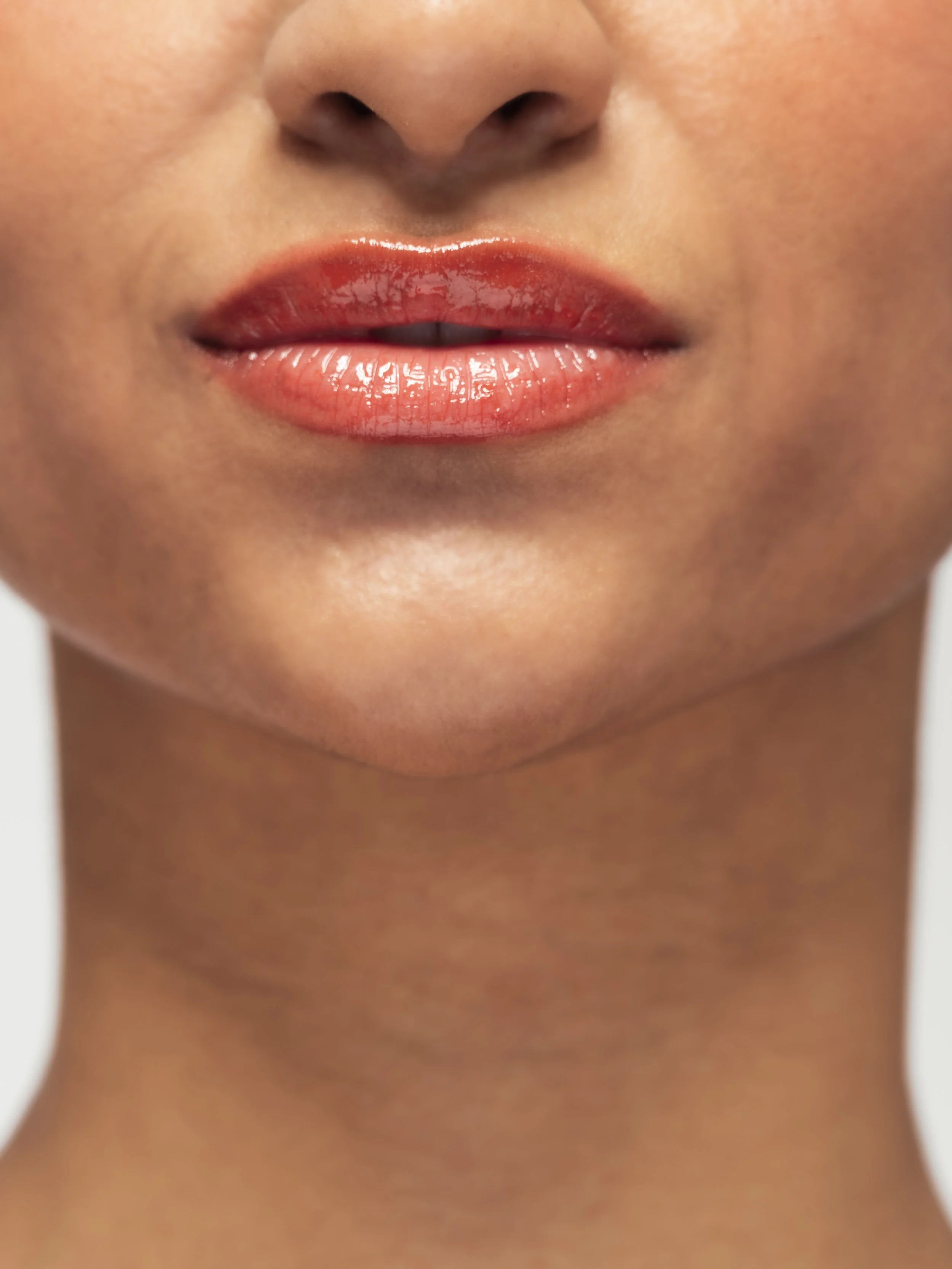 Zoom sur les lèvres maquillées avec un gloss glossy.