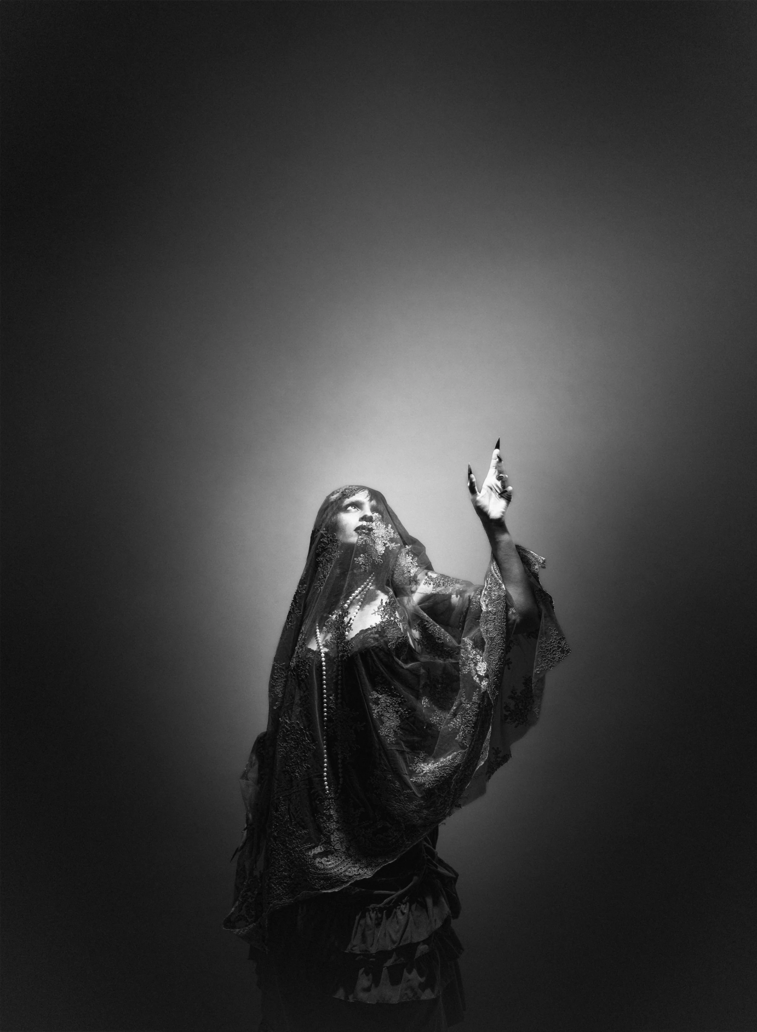 Une femme portait un voile en dentelle dans une pose artistique, en noir et blanc.