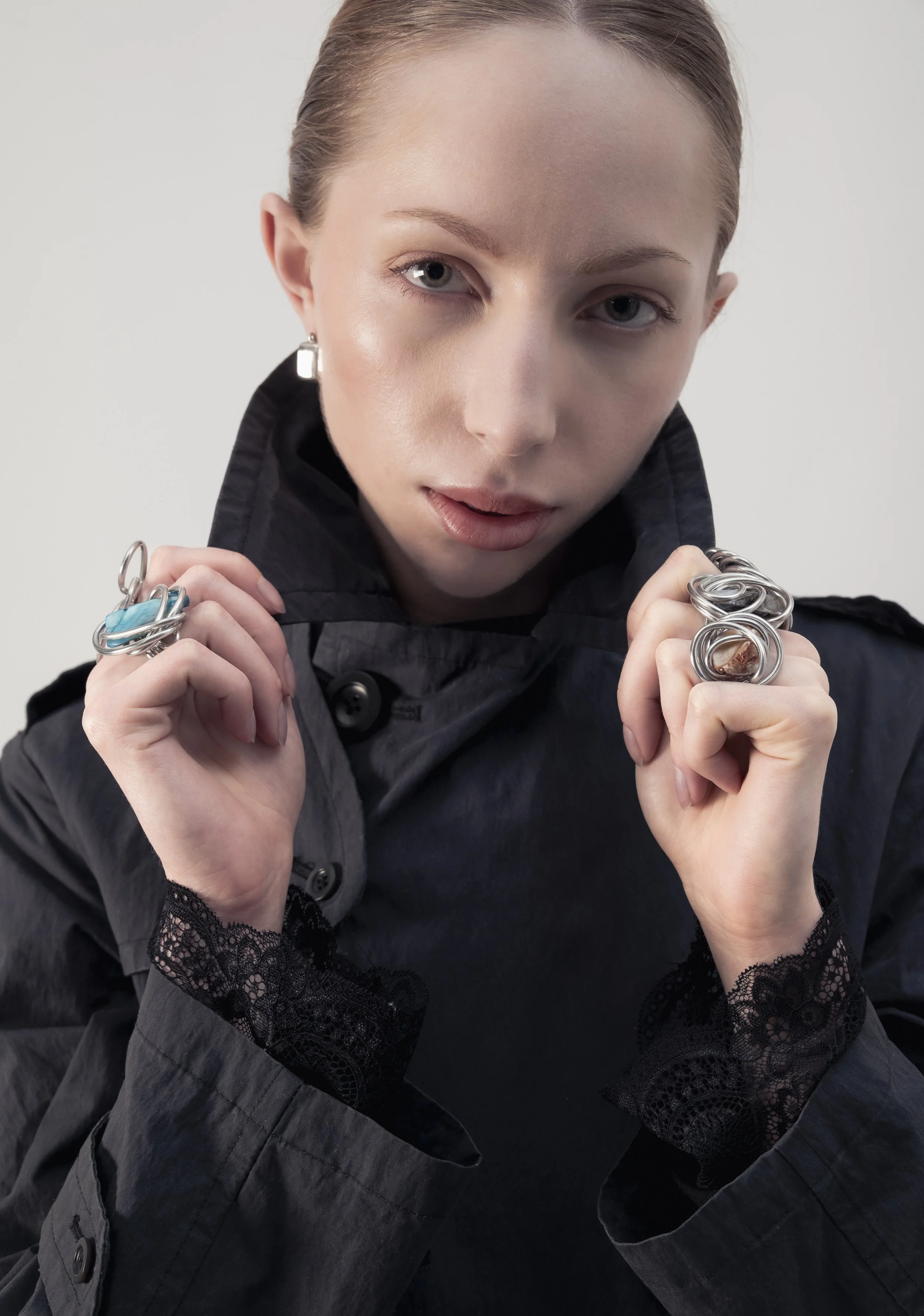 Jeune femme avec des bijoux en argent, portant une veste noire avec des détails en dentelle, regardant l'objectif.