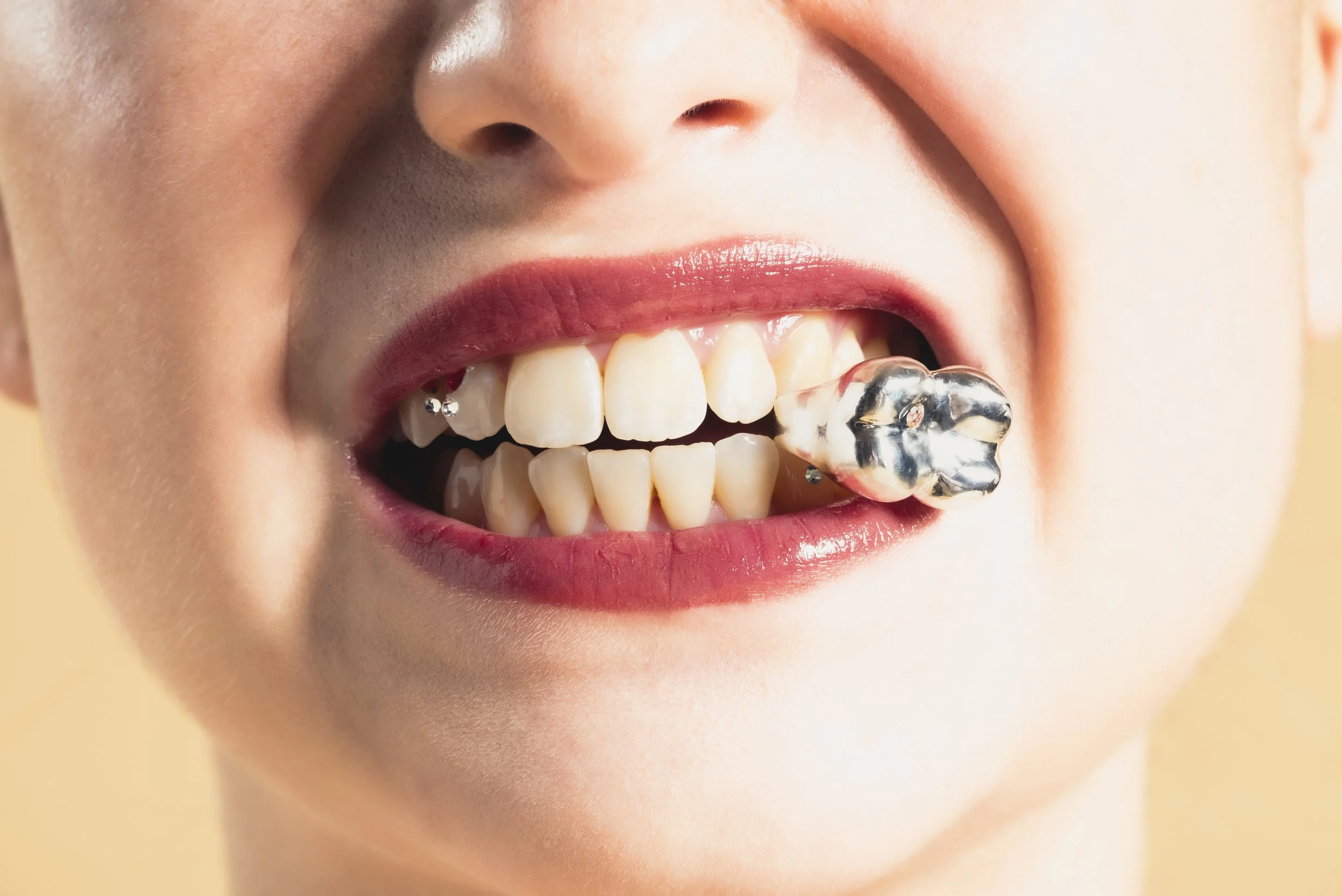 Femme mordant une dent artificielle en or rose dans sa bouche