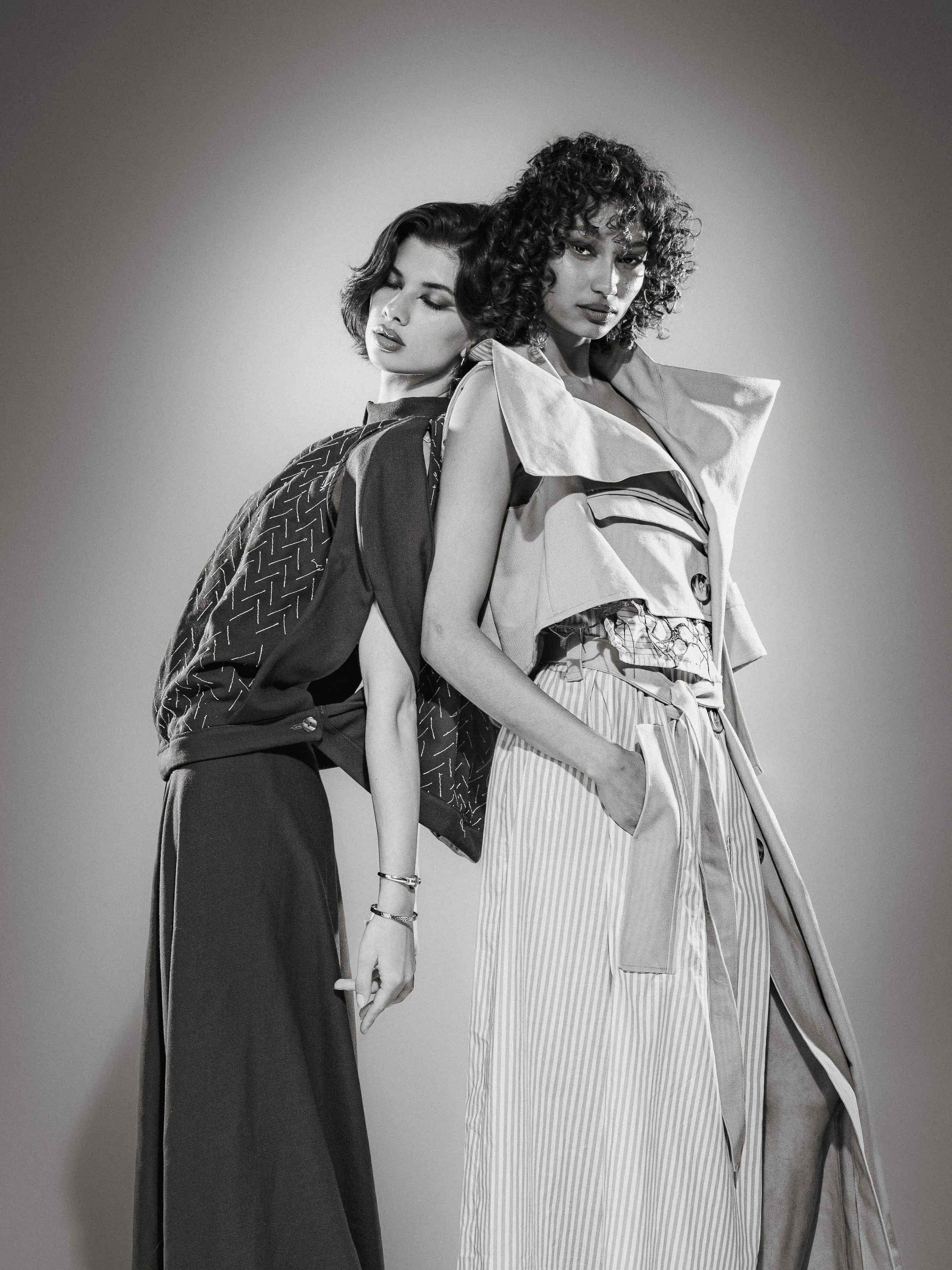 Deux femmes posant ensemble, vêtues de vêtements élégants dans une photo en noir et blanc.