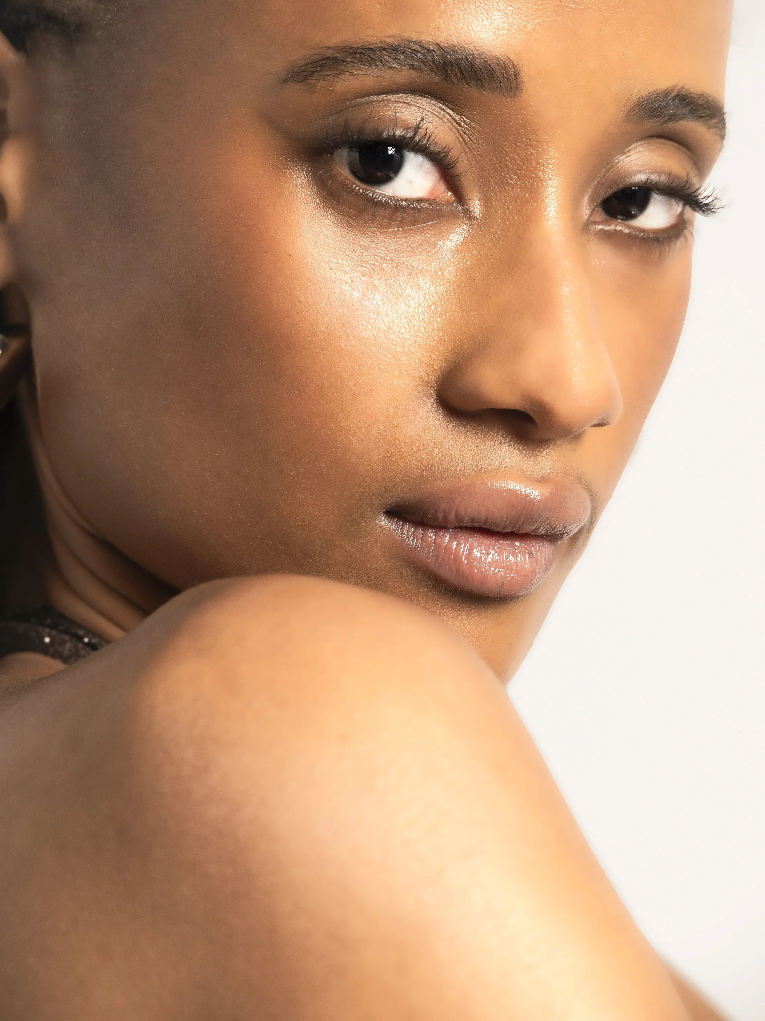 Un gros plan du visage d'une femme avec une peau claire, maquillage naturel, regardant vers l'objectif, avec un fond blanc