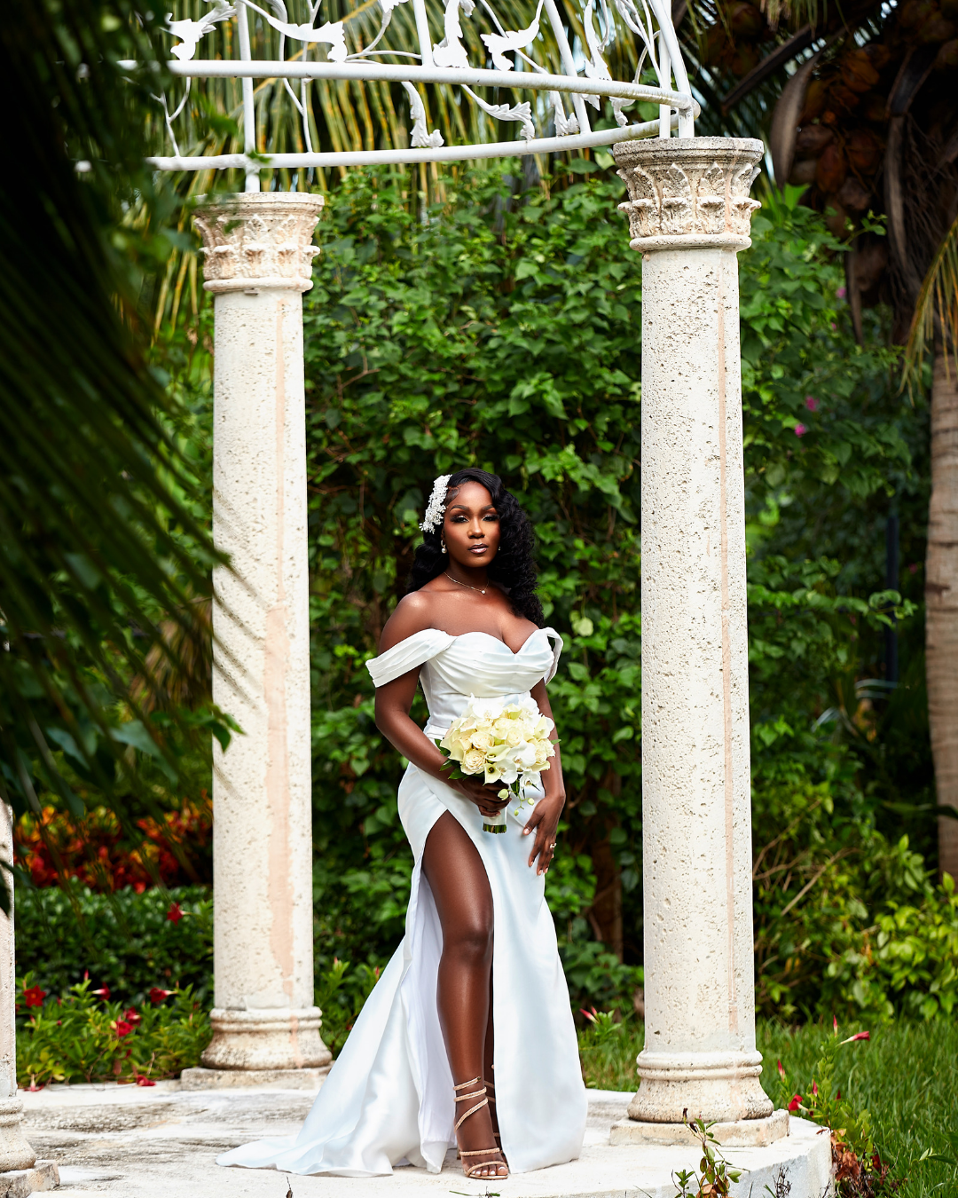 Bride posing beneath a garden gazebo holding a bouquet