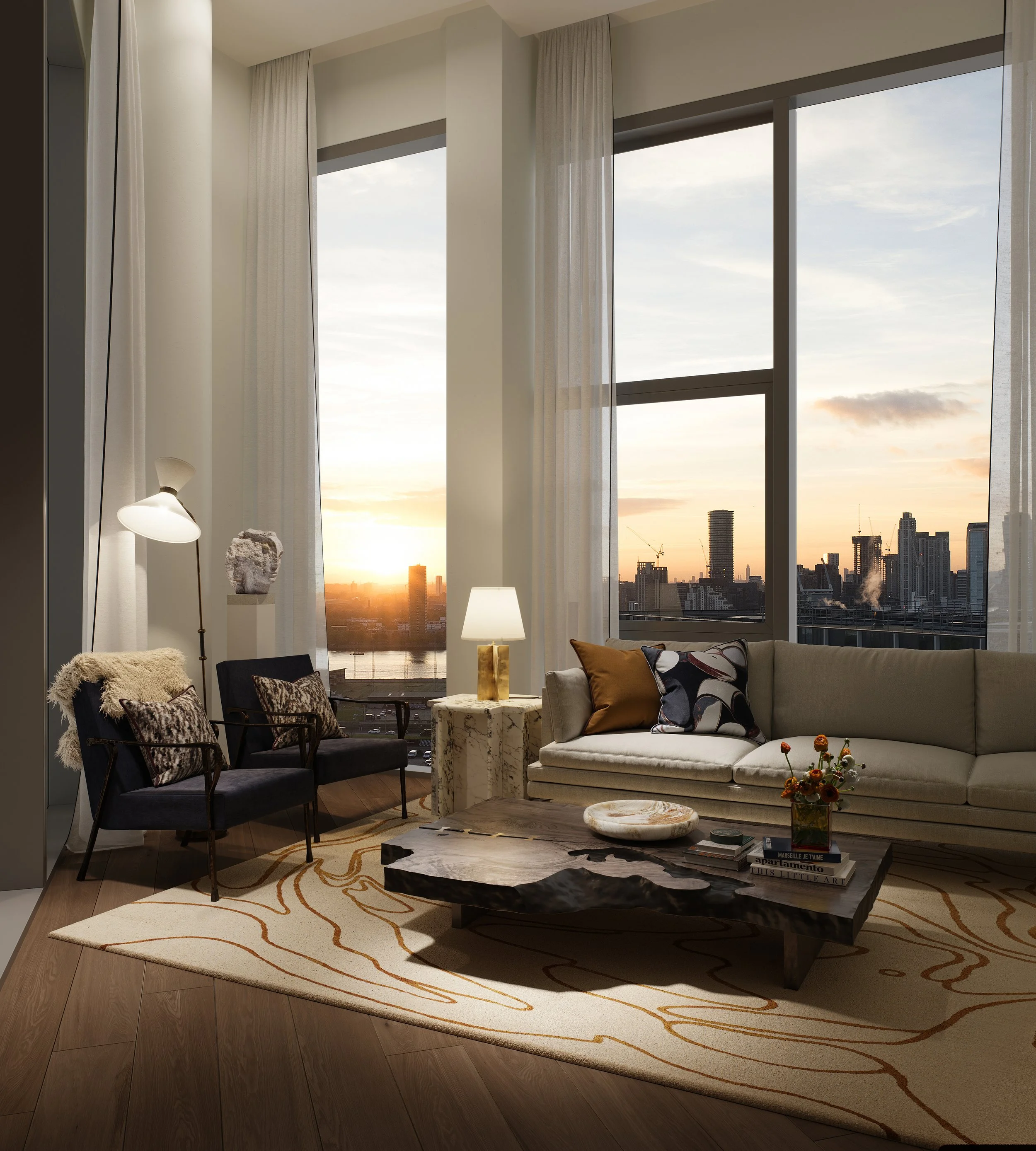 Living room with large windows showing a city skyline at sunset, featuring a cream sofa with pillows, a coffee table with decorative items, two black chairs with pillows, a floor lamp, and a rug with orange patterns.