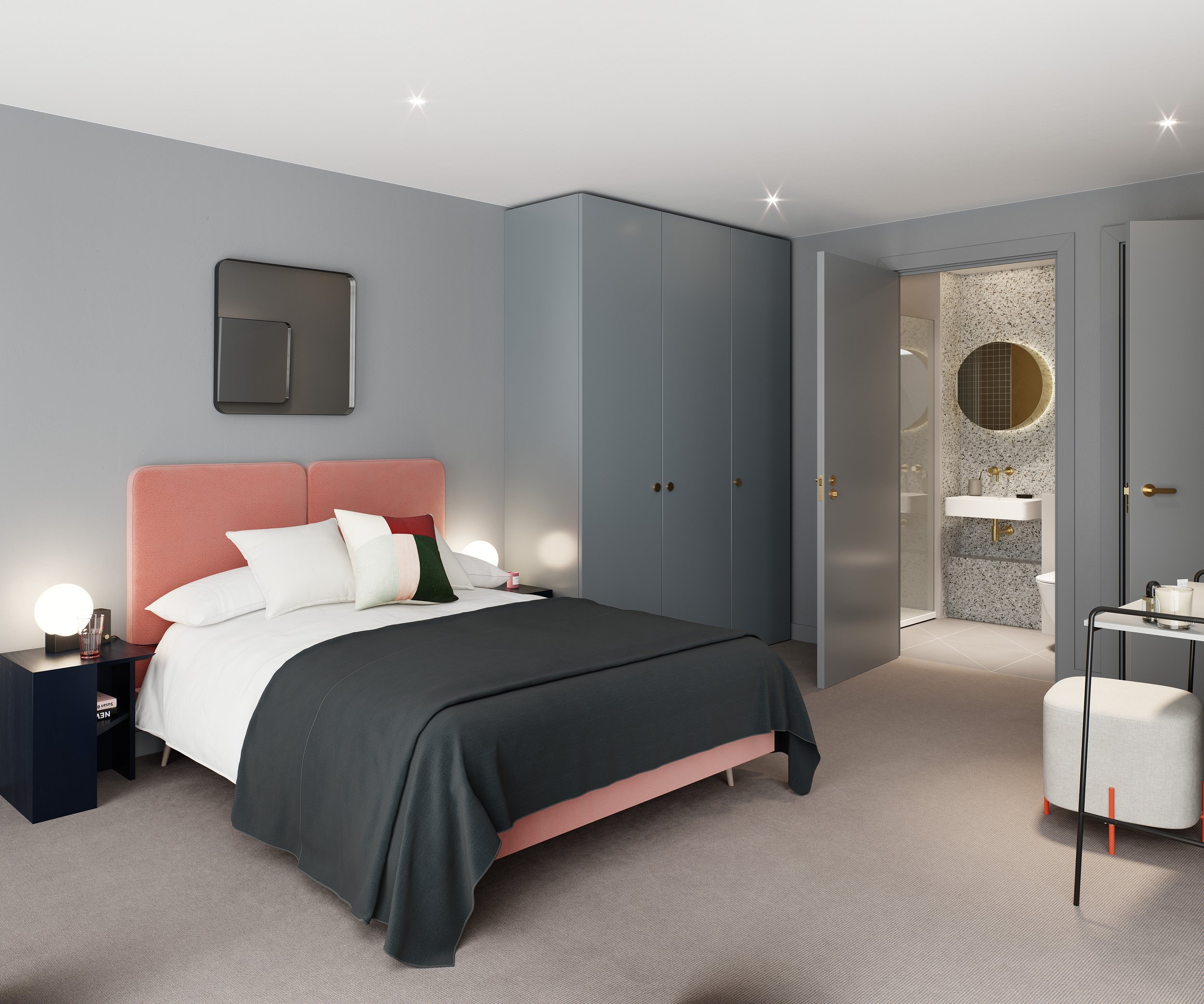 Modern bedroom with pink upholstered headboard, white bedding, and dark gray blanket. Nightstands with lamps, a blue wardrobe, and a small sitting area with a round white ottoman and black tray. An open door leads to a bathroom with a round mirror an