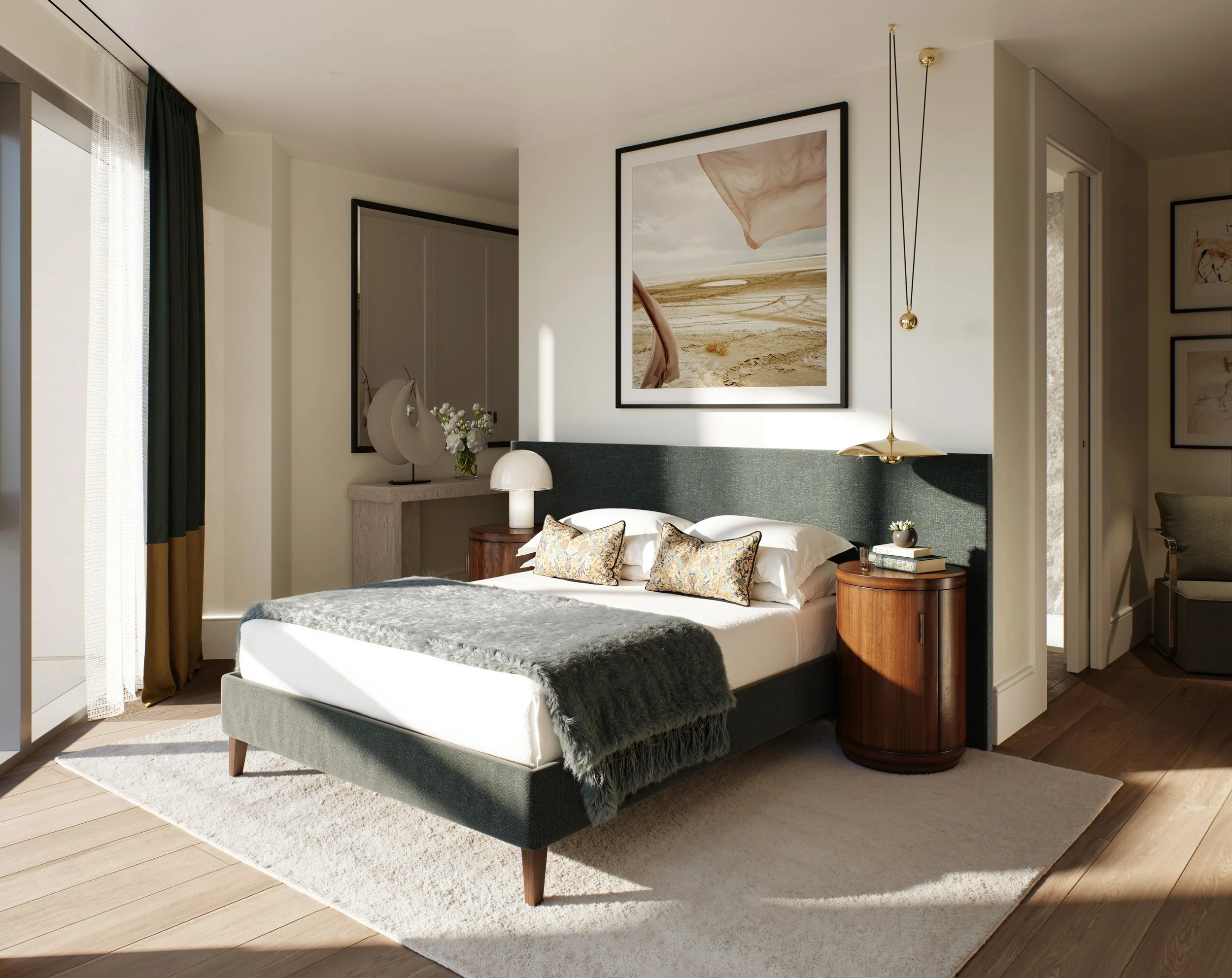 A modern bedroom with a large bed, dark green upholstered headboard, white bedding, and decorative pillows. There are two wooden bedside tables with lamps, one with a rounded base and the other with a stack of books and a small plant. Artwork hangs a