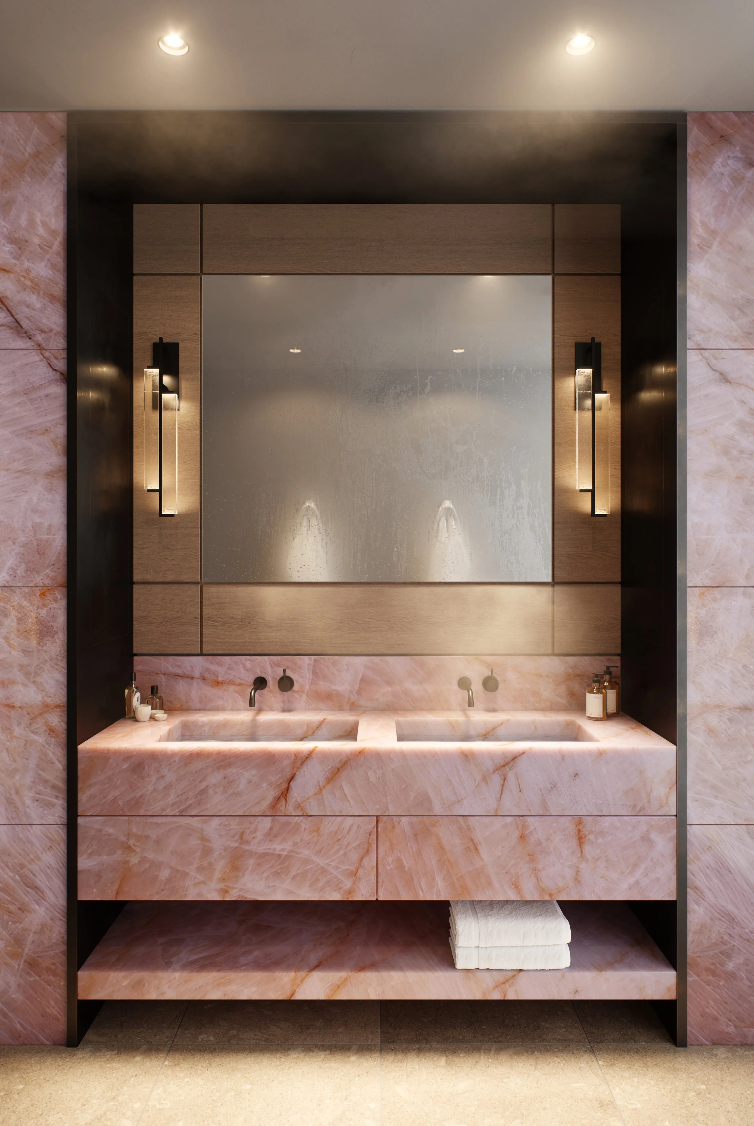 Bathroom with pink marble sink, two soap dispensers, mirror, and modern black and gold lighting fixtures.