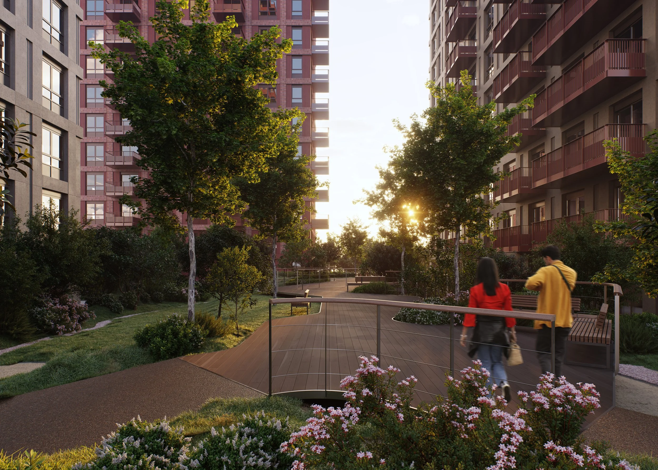 Two people walking on a curved wooden pathway in a residential courtyard during sunset, surrounded by trees and pink flowering plants, with tall apartment buildings on either side.